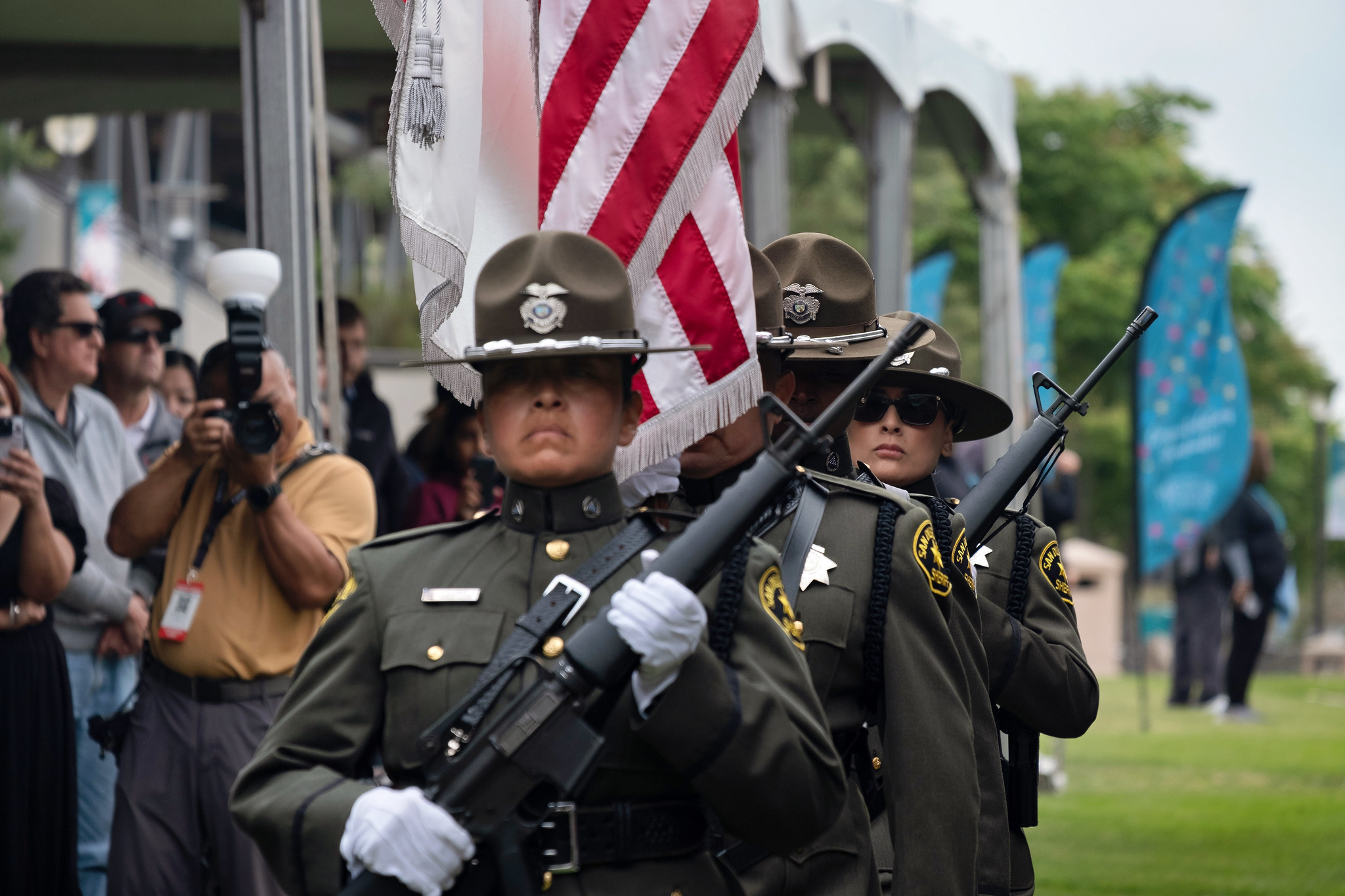 
Four people in Sheriff's Department uniforms holding flags and rifles enter to begin the commencement ceremony.

