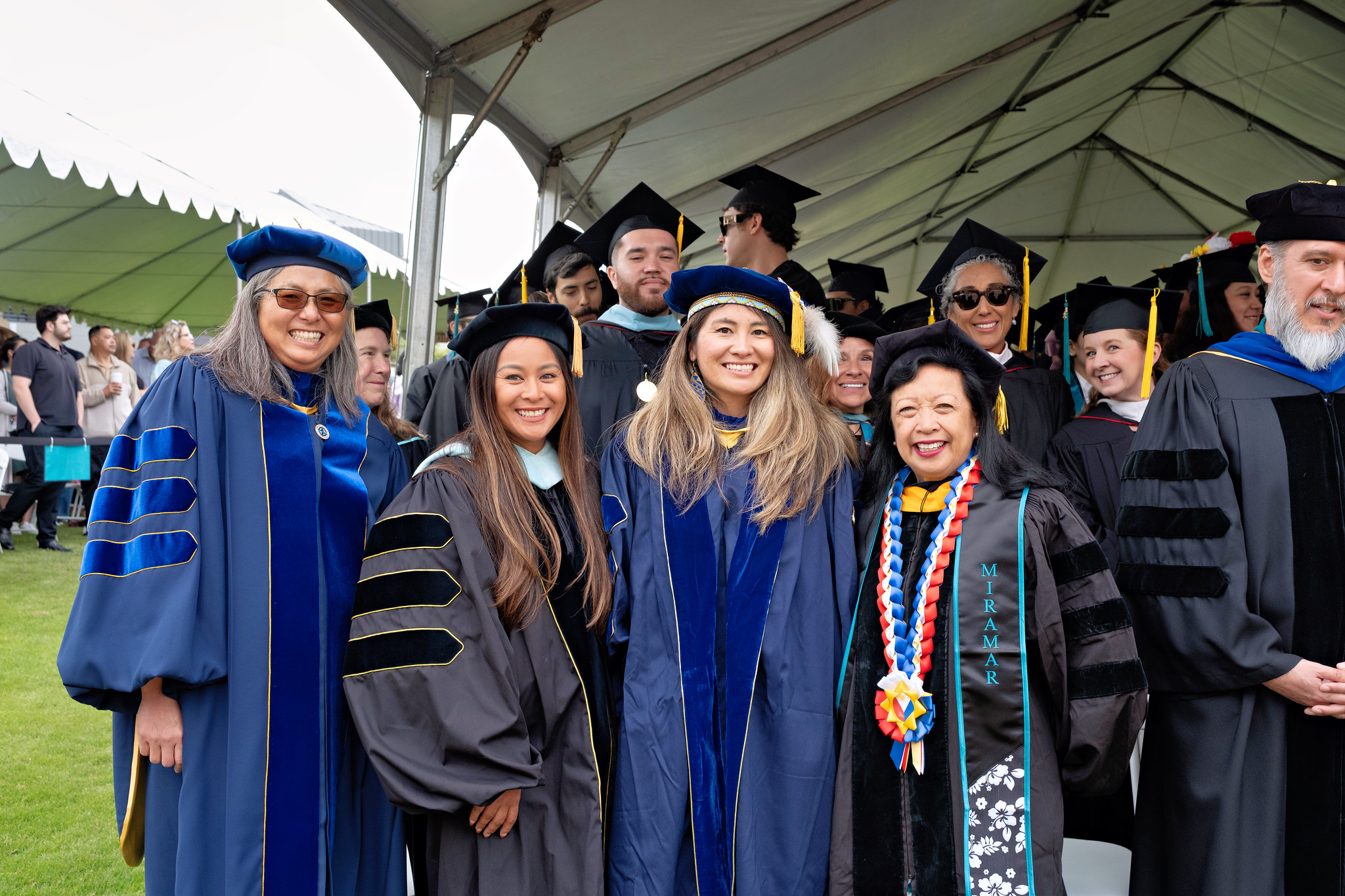 
Eleven faculty members in caps and gowns taking their seats.
