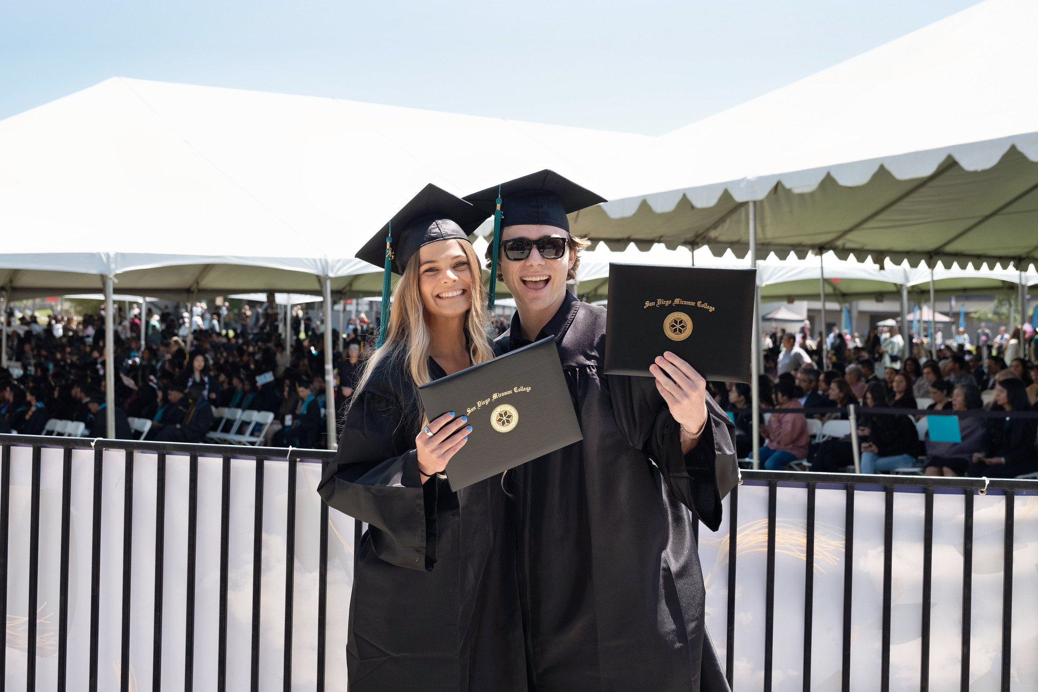 
A couple hugs and shows off their degrees.
