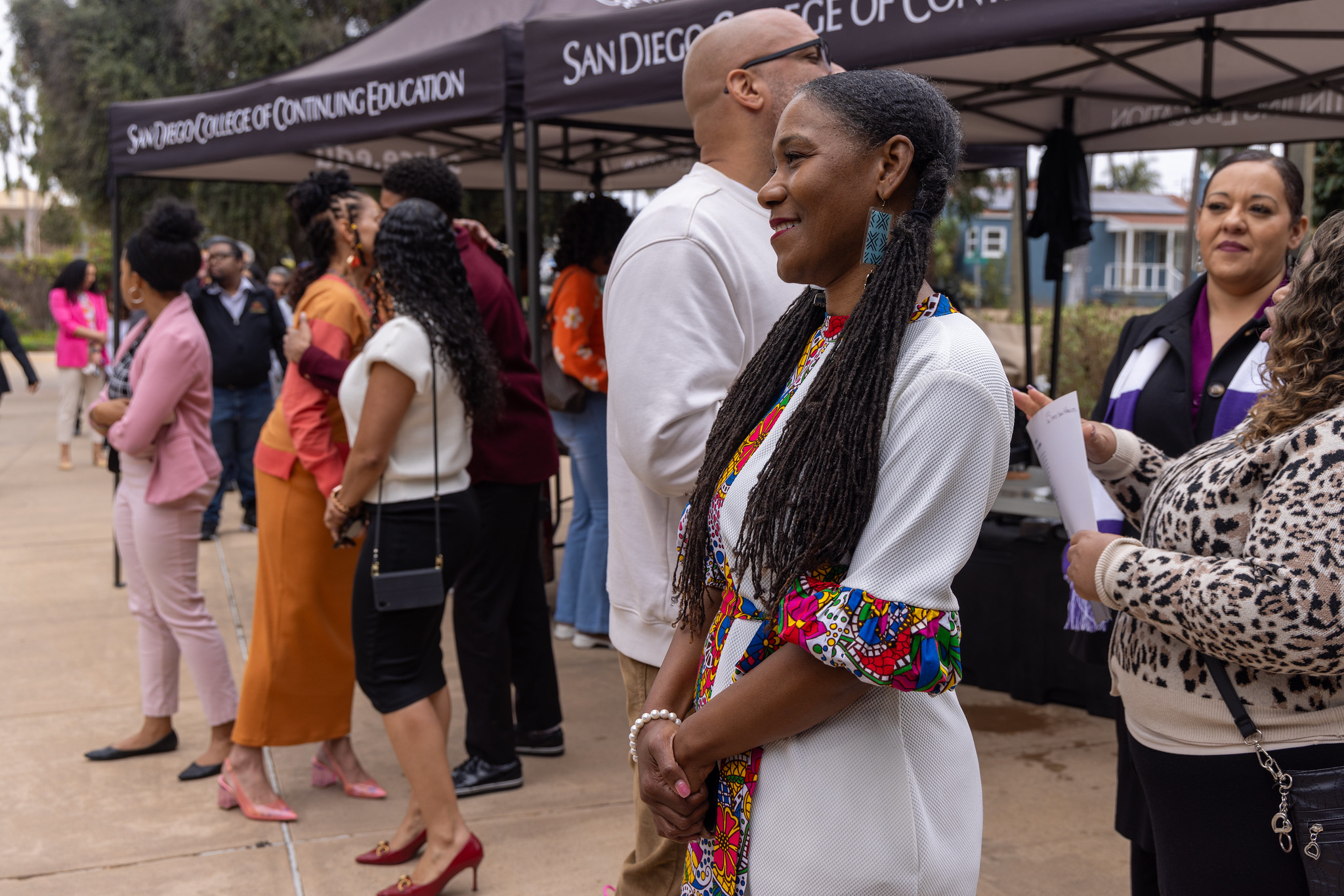 
A lady in a white dress smiles and looks on during a Black History Month event at the Educational Cultural Complex.
