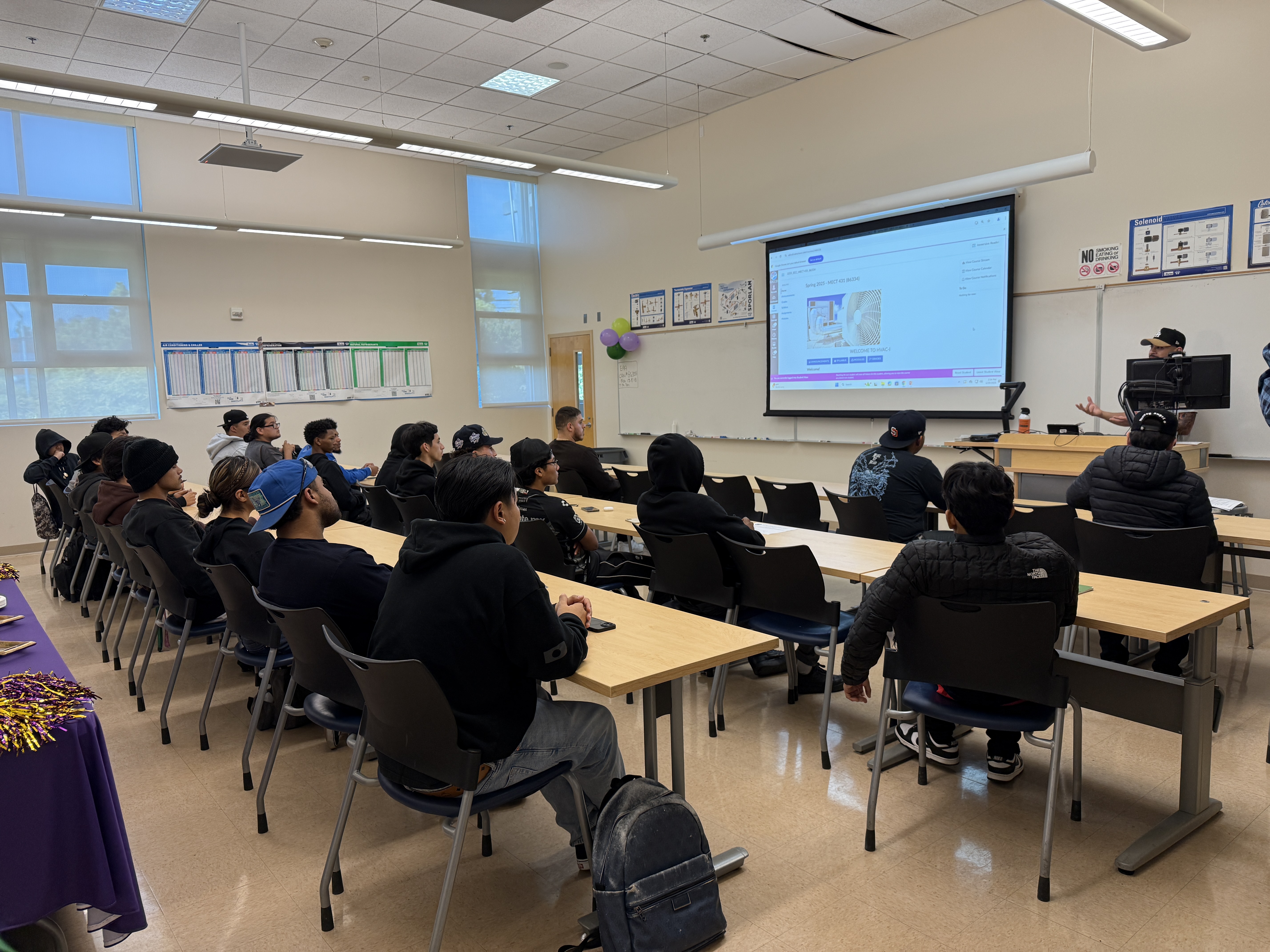 
College of Continuing Education students in a classroom looking at a screen at the front of the class.
