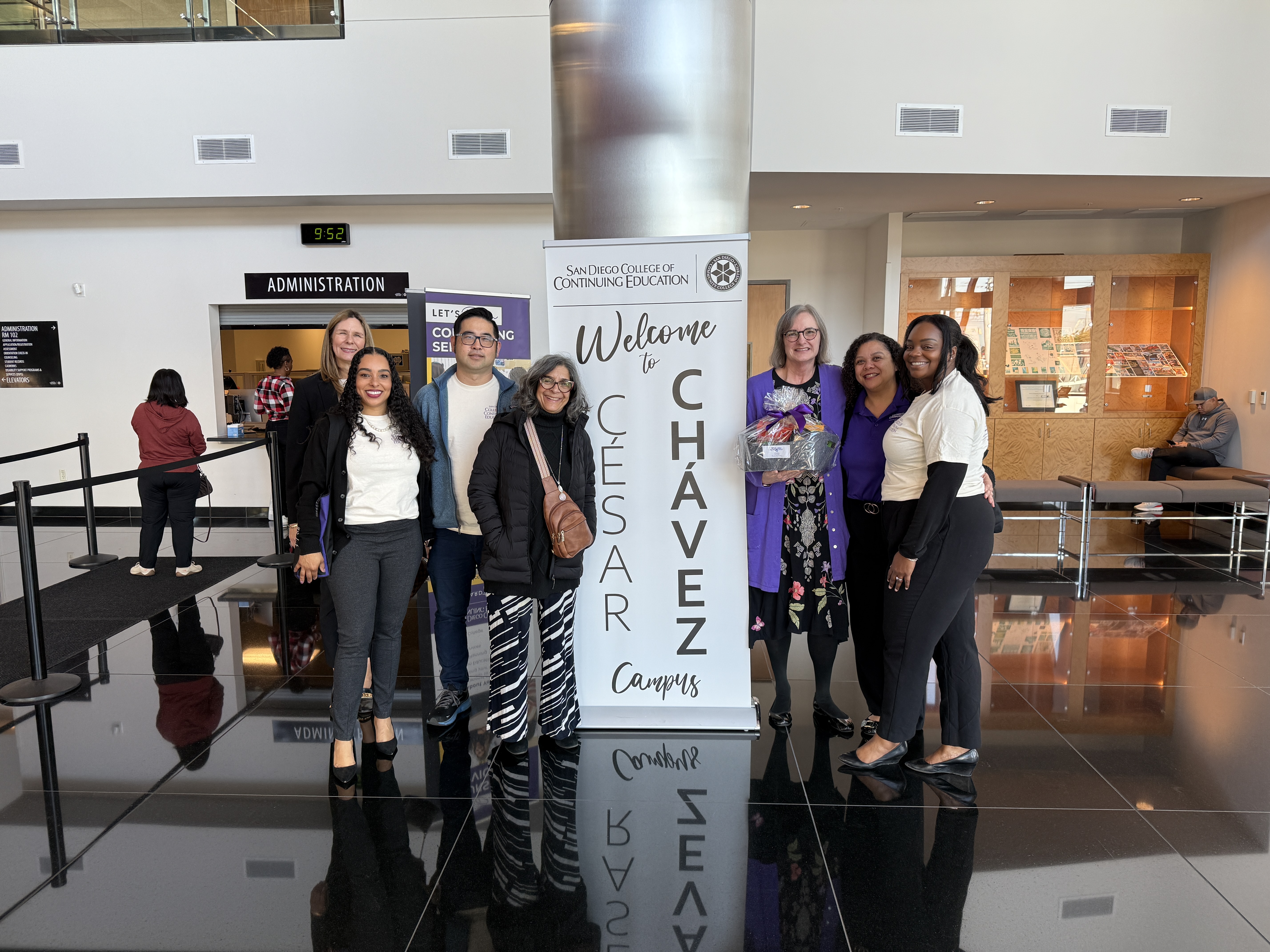 
Six people stand around a welcome banner at the Cesar Chavez campus.
