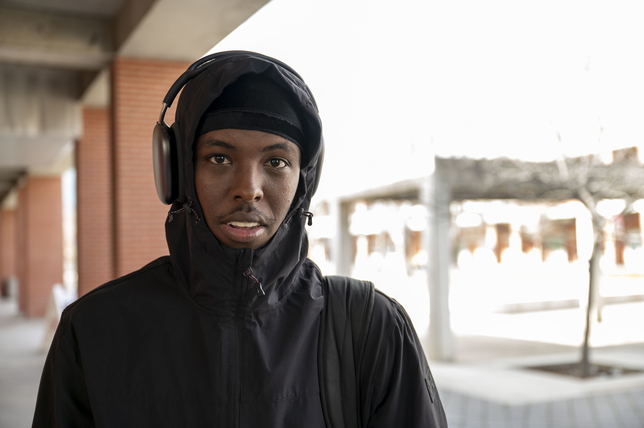 
A City College wearing a black hoodie and headphones.
