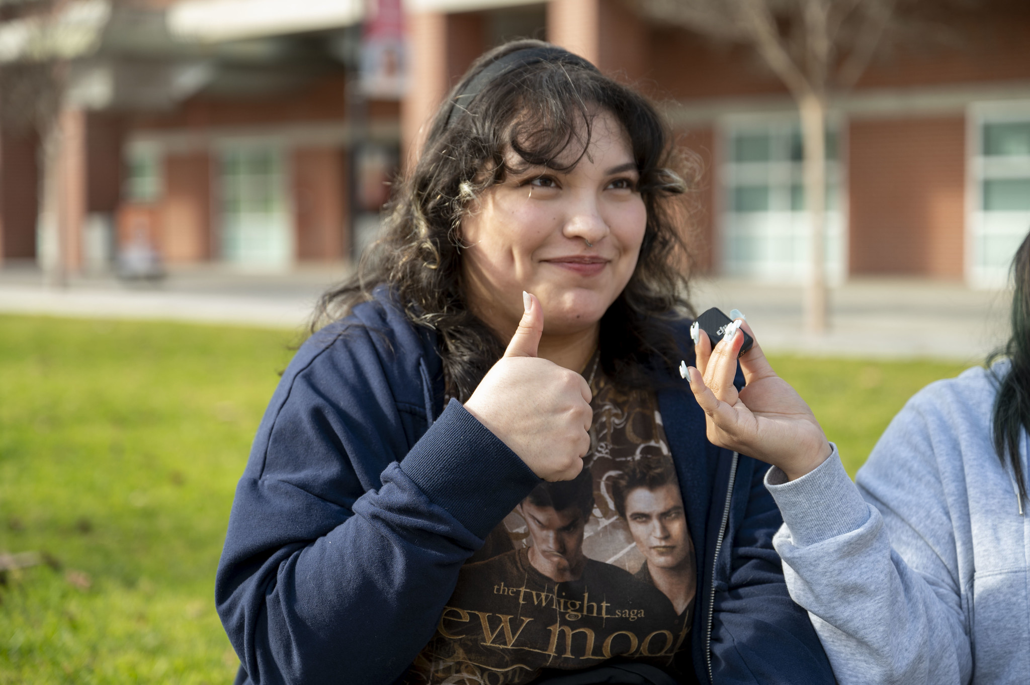 
A City College student sitting on the grass with some friends gives a thumbs up.
