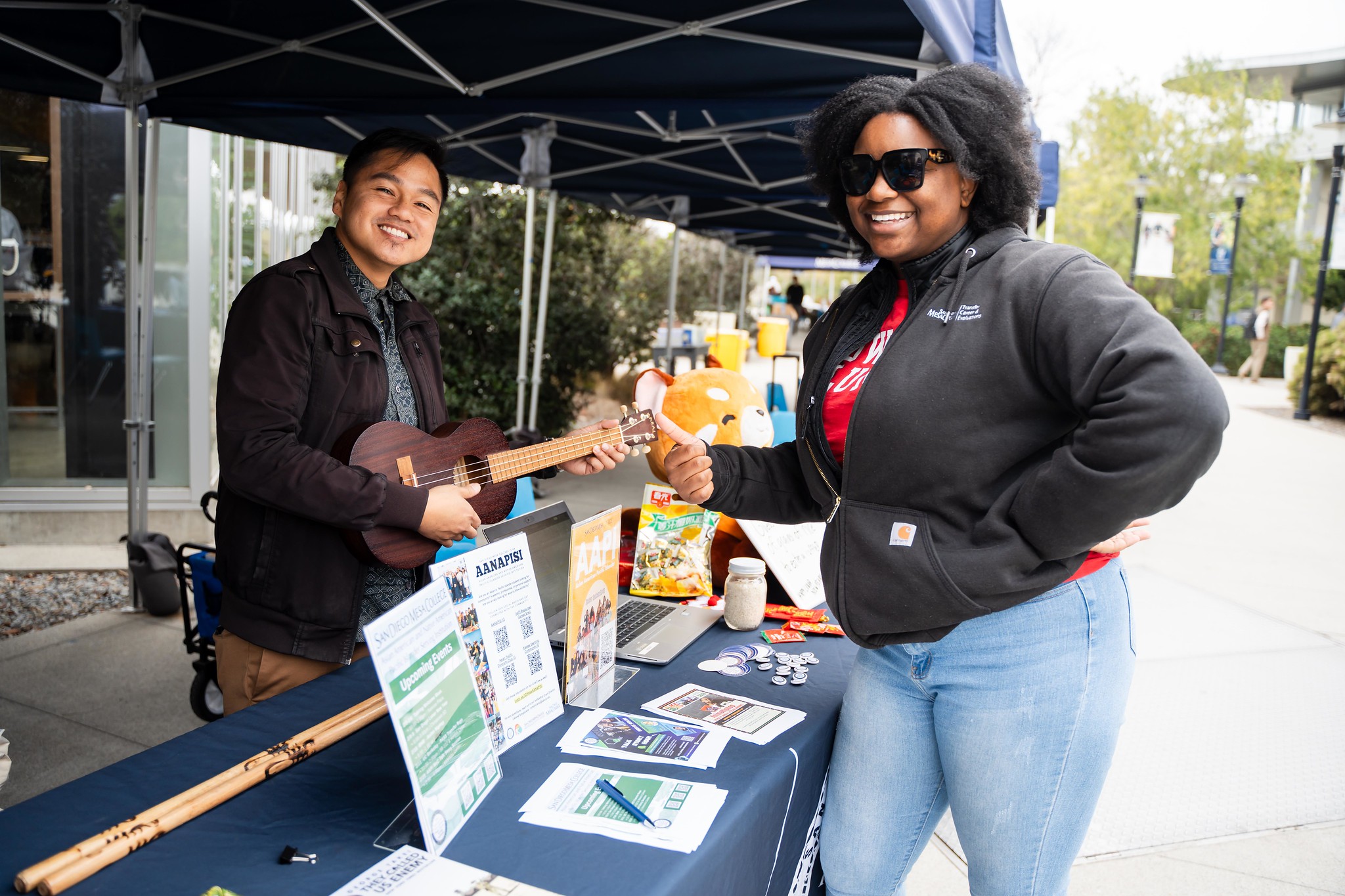 
Two people at Mesa College booth. One is playing a guitar.
