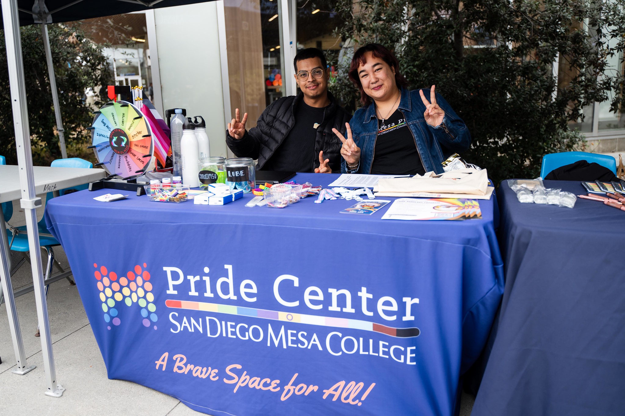 
Two people give peace signs at the Pride Center booth at Mesa College.

