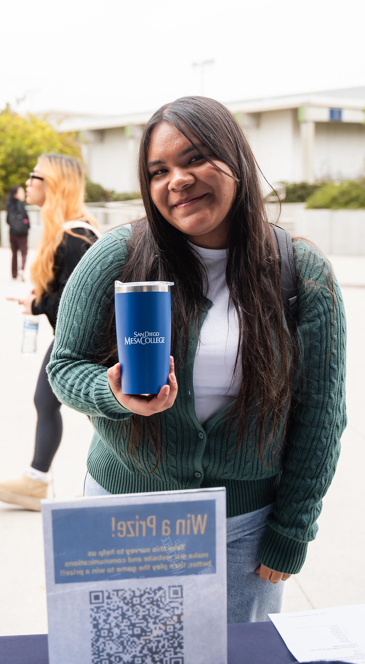 
A student holds up a Mesa College tumbler cup that was given away during welcome week.
