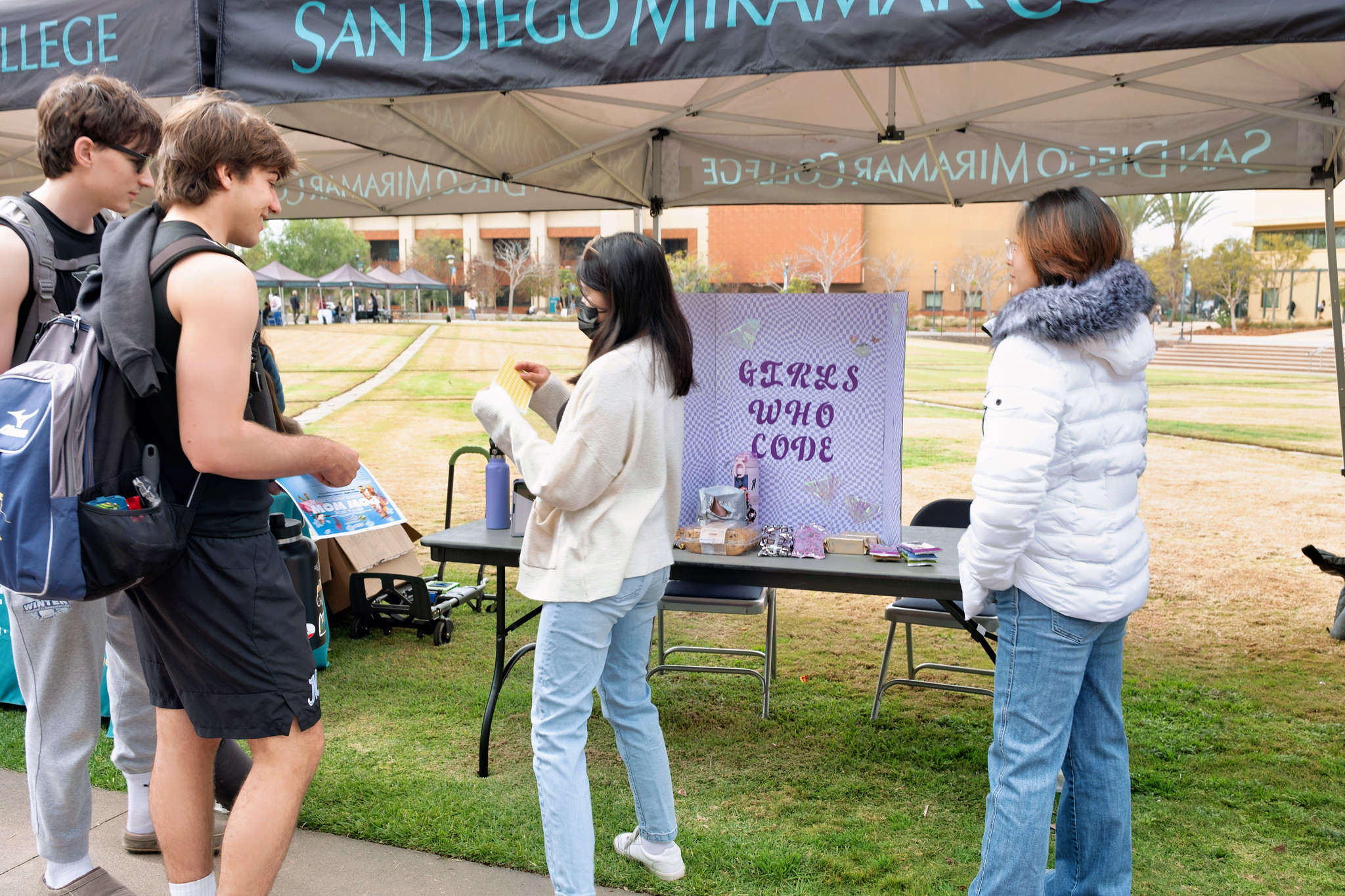 
Four Miramar students at a booth. A sign says girls who code.
