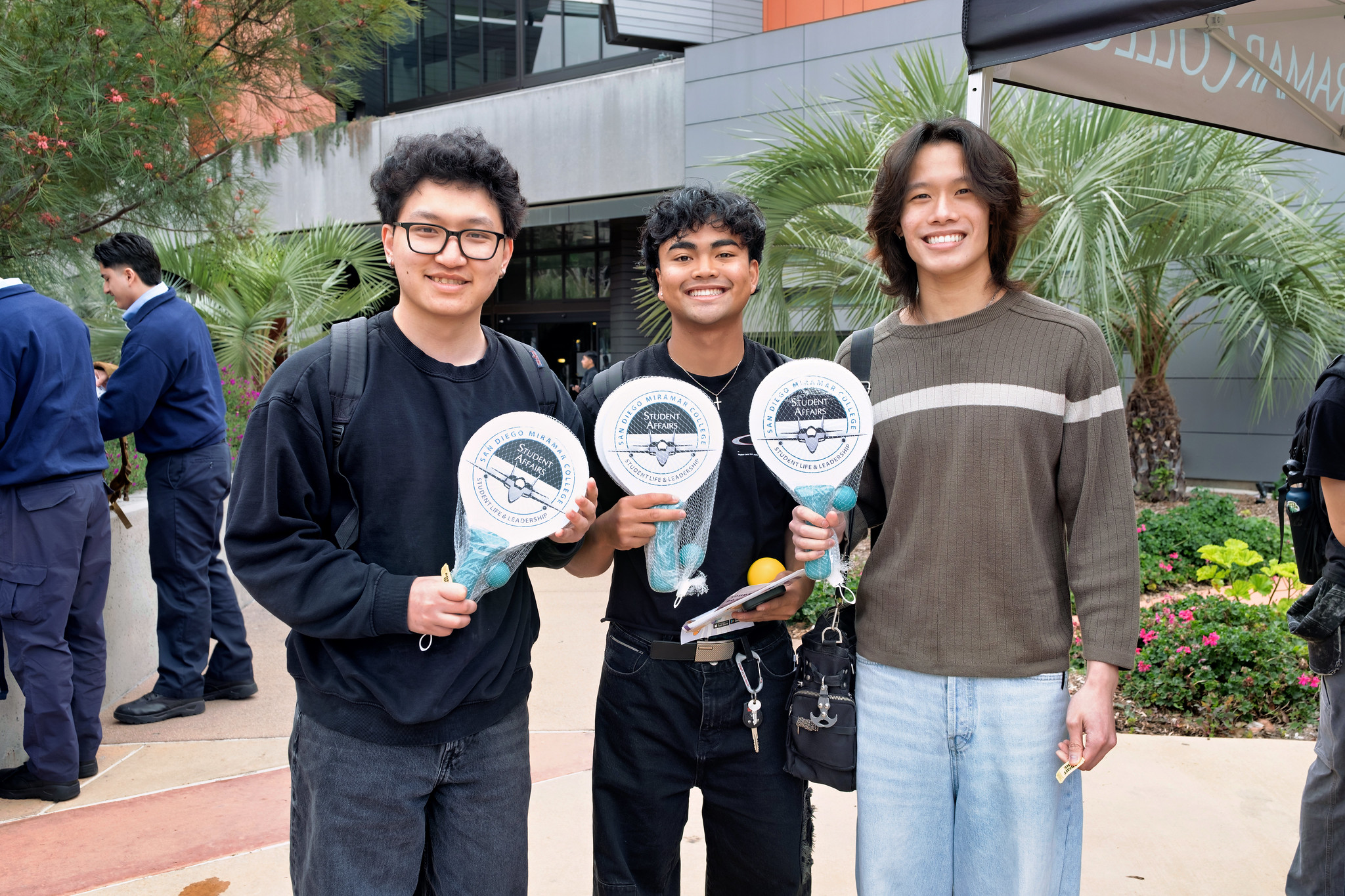 
Three students hold up paddle ball sets that were given away during Miramar College's welcome week.
