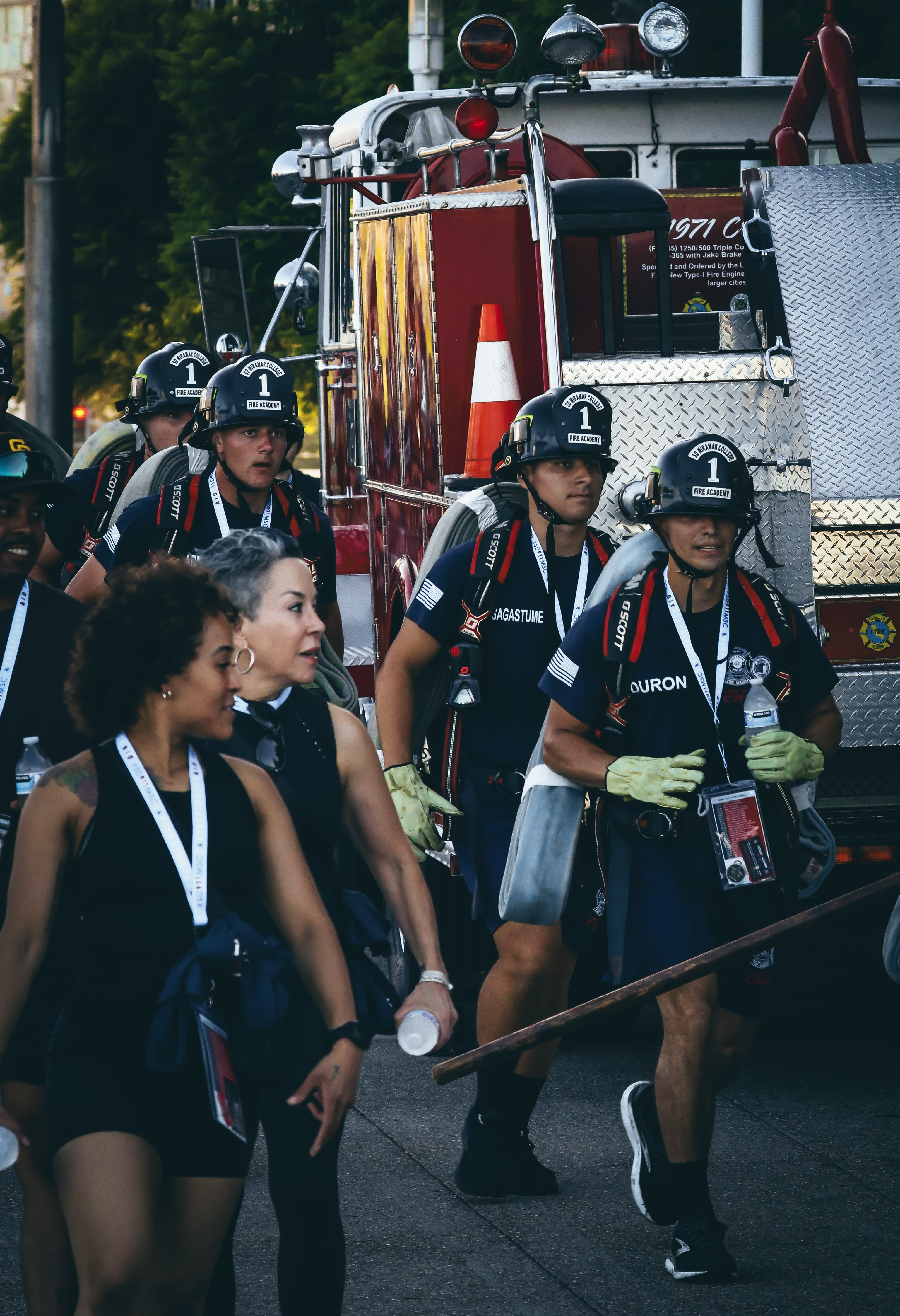 
Four cadets in blue t-shirts and shorts and black fire helmets carry their fire gear in the stair climb.&nbsp;
