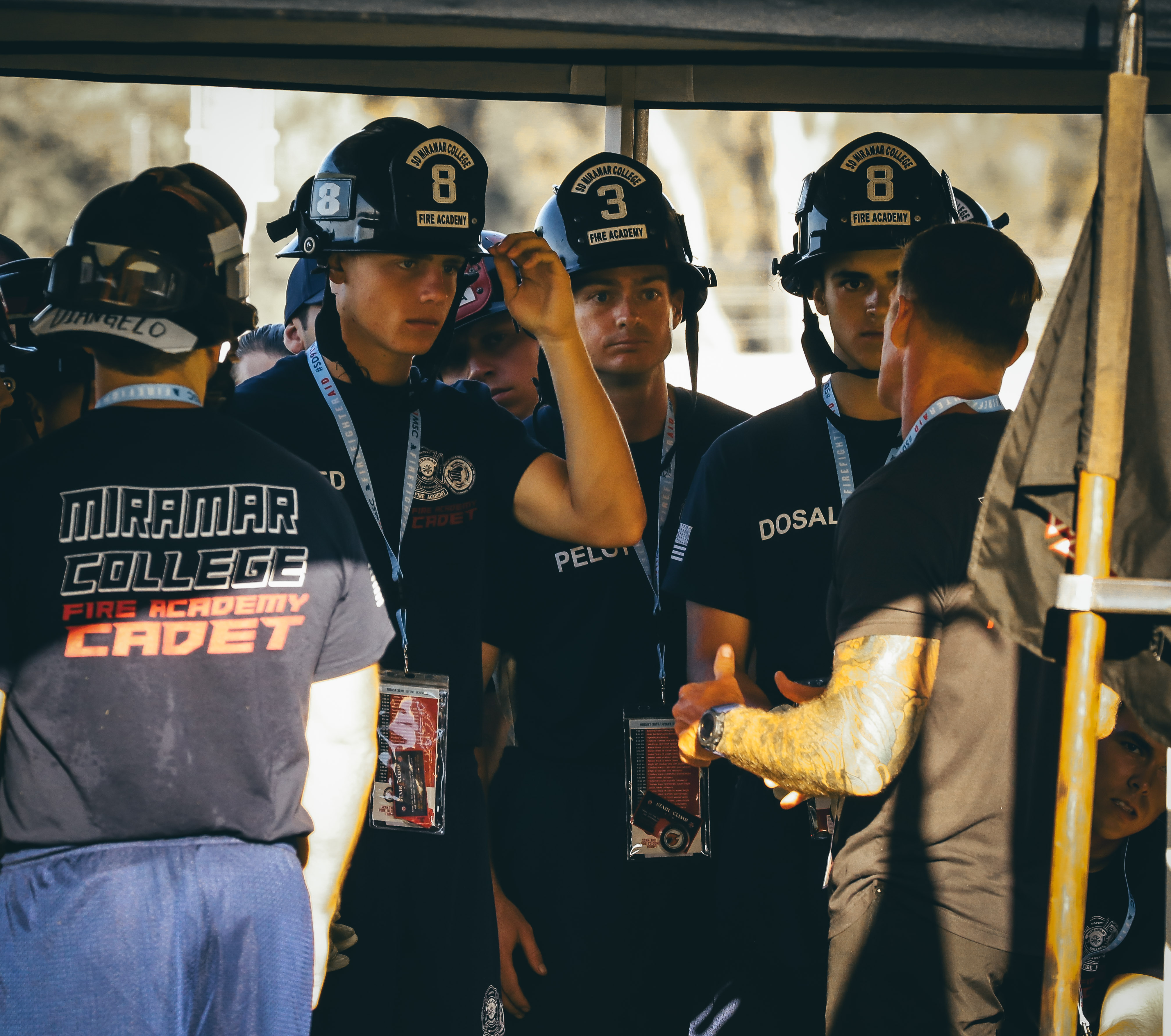 
Cadetes in fire helmets gather under a tent.&nbsp;
