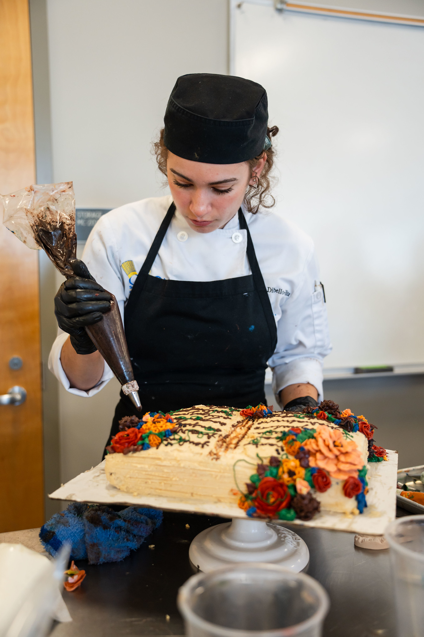 
A chef uses a piping bag to decorate a cake. 
