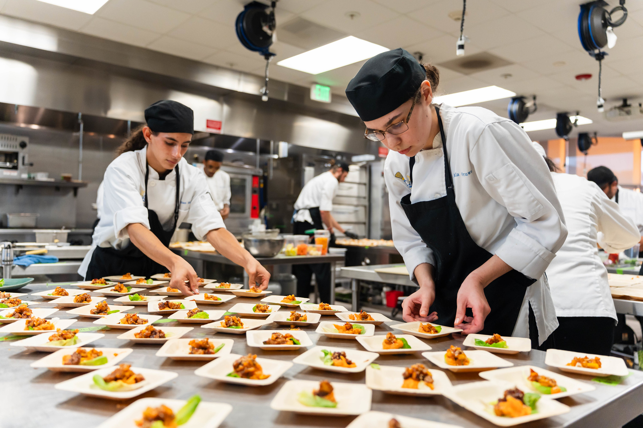
Two chefs in a prep area putting together samples.
