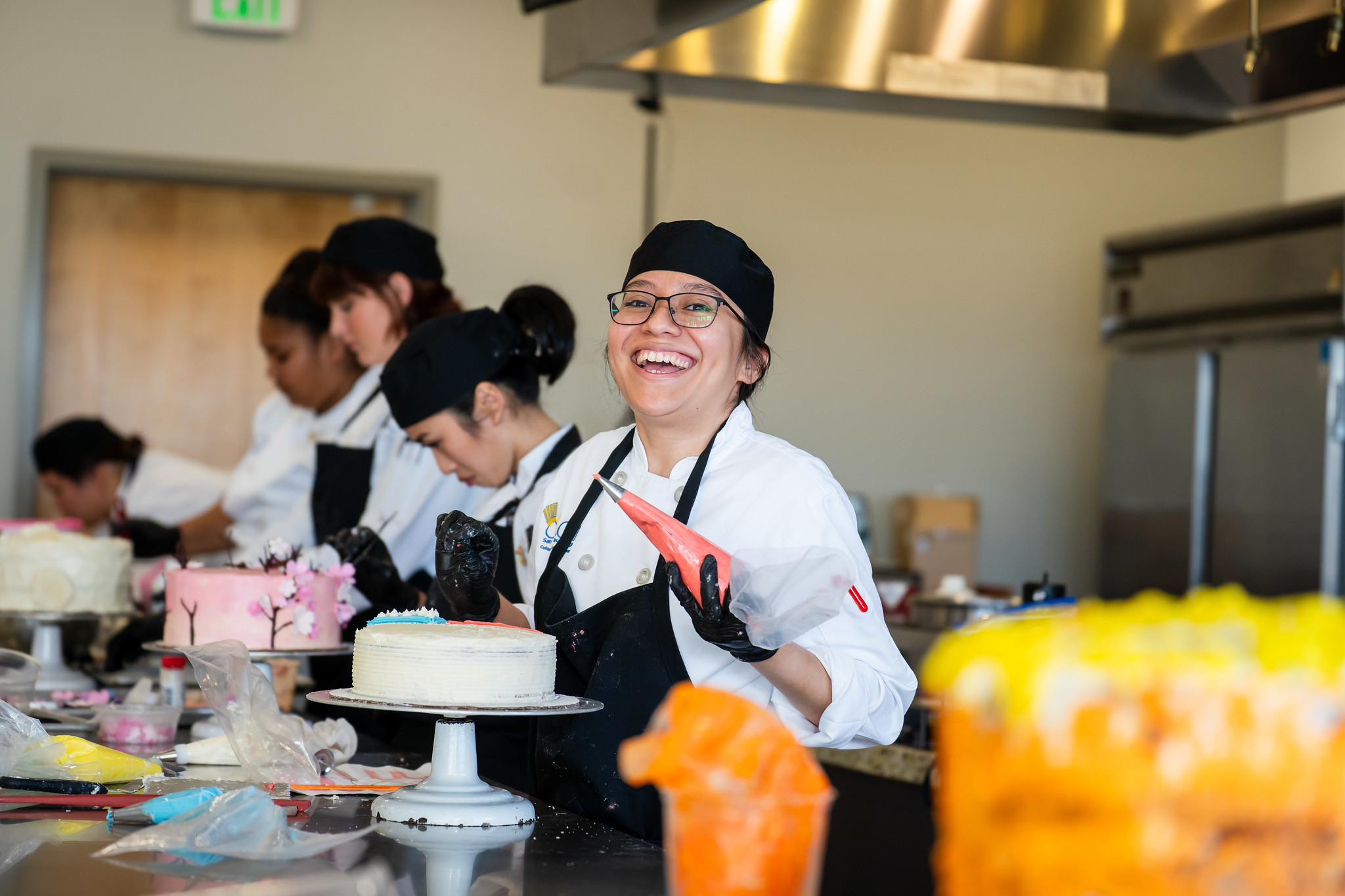 
A row of chefs decorating cakes.
