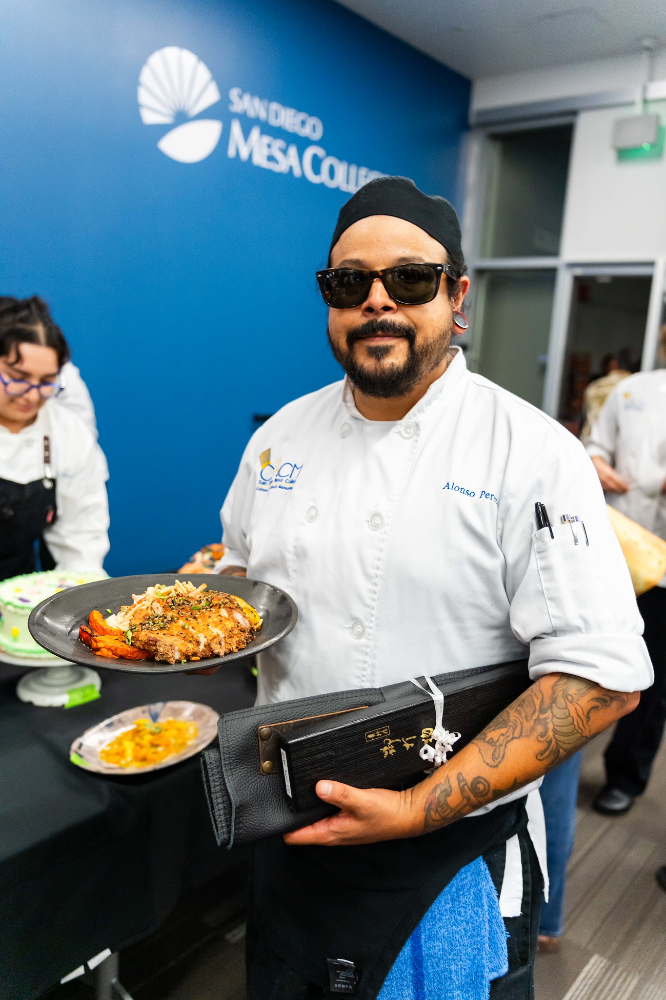 
A chef holds up a plate of chicken that won best dish 
