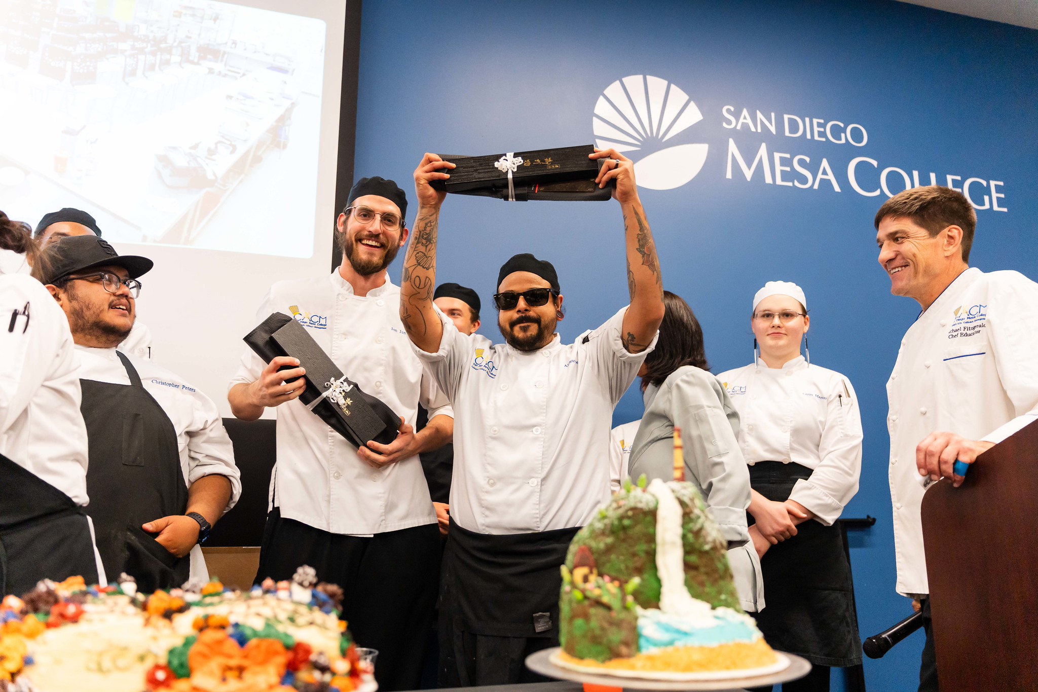 
The winner of best dish holds up a set on knives he won.
