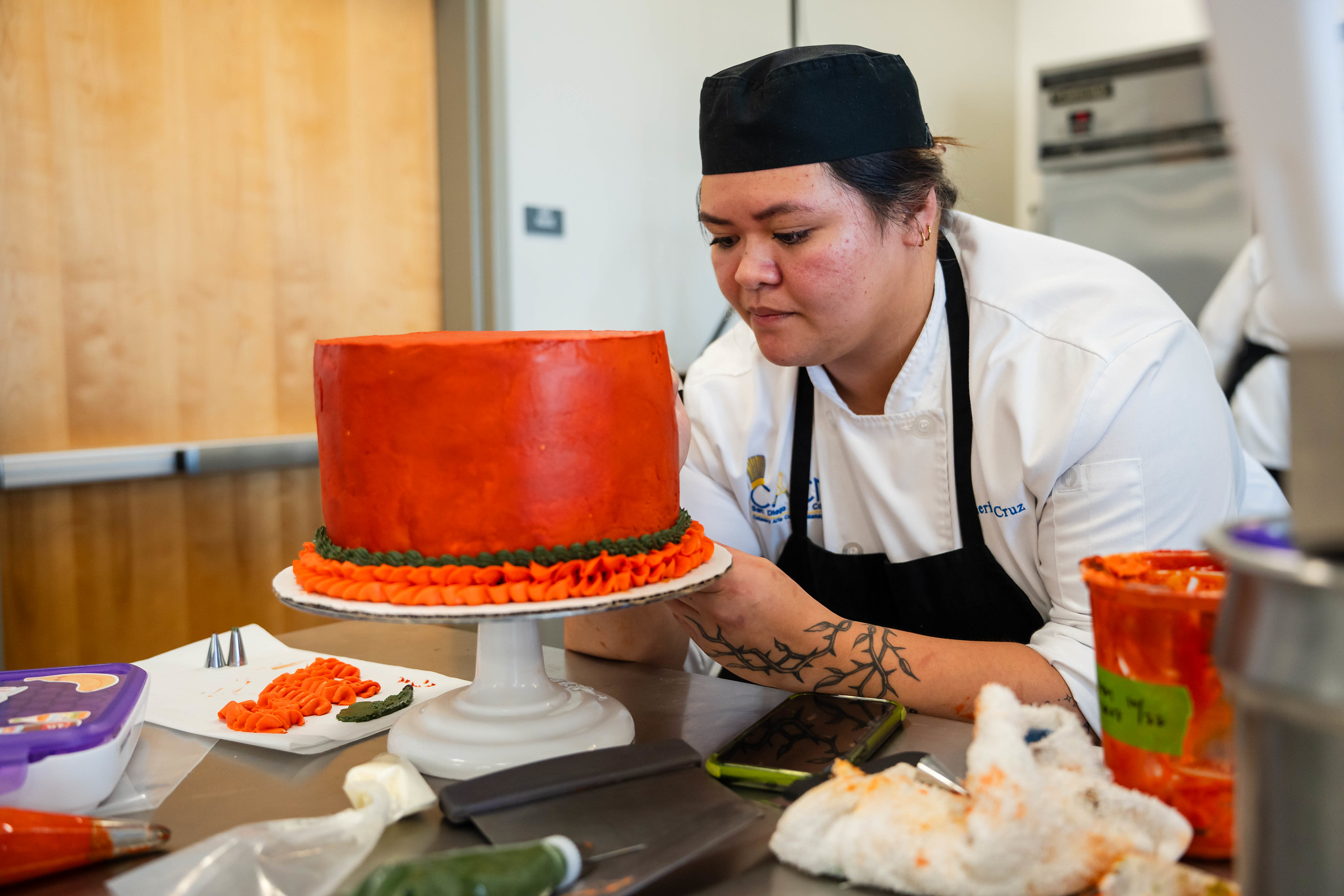 
A chef decorating a red cake.
