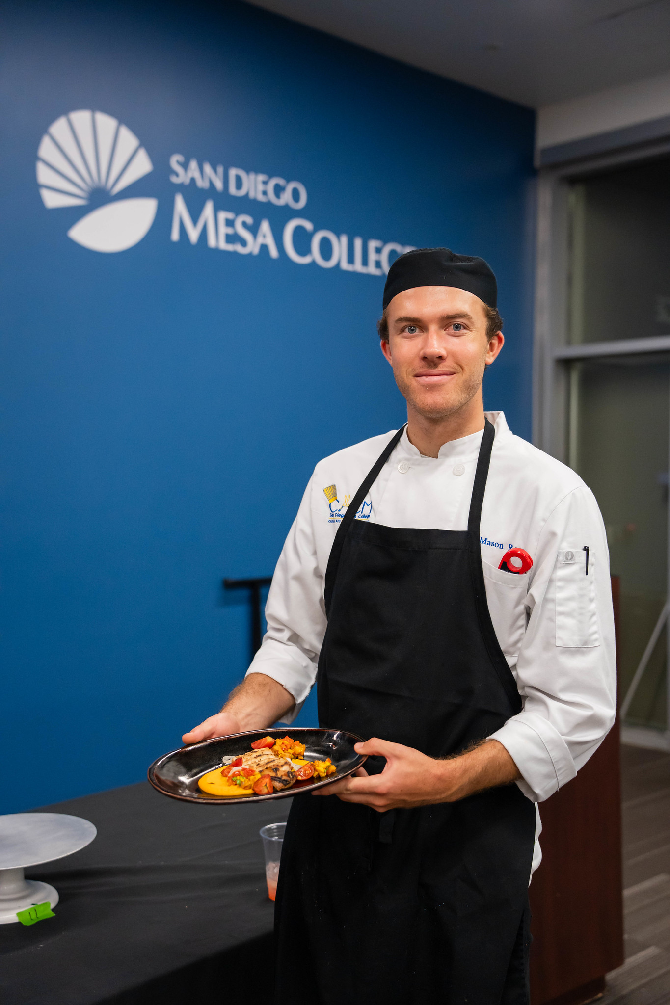 
A chef holds up a plate of food he prepared. 
