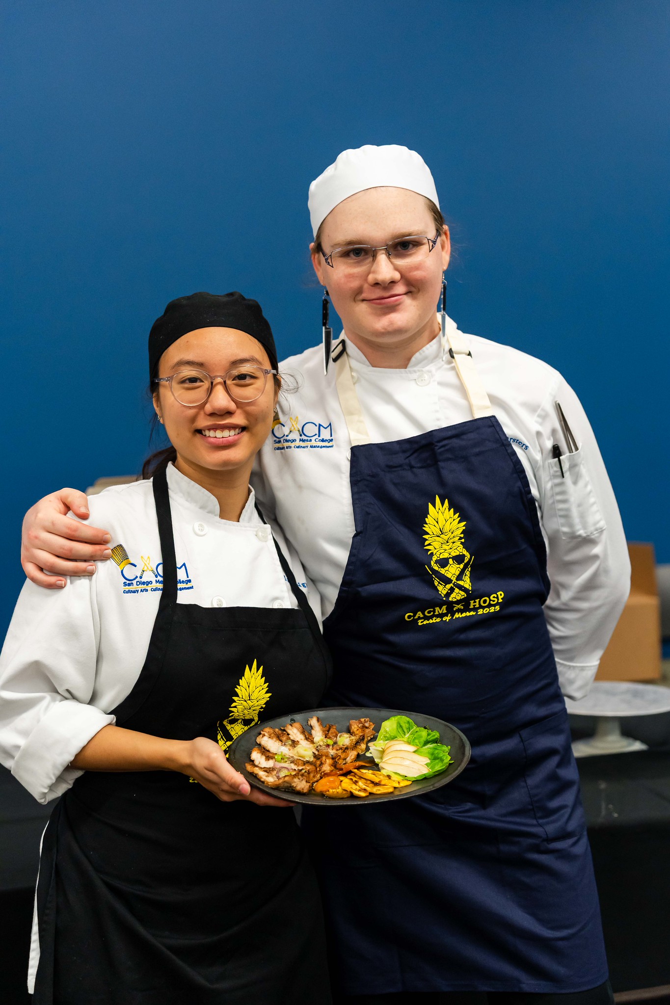 
Two chefs present a plate of food. 
