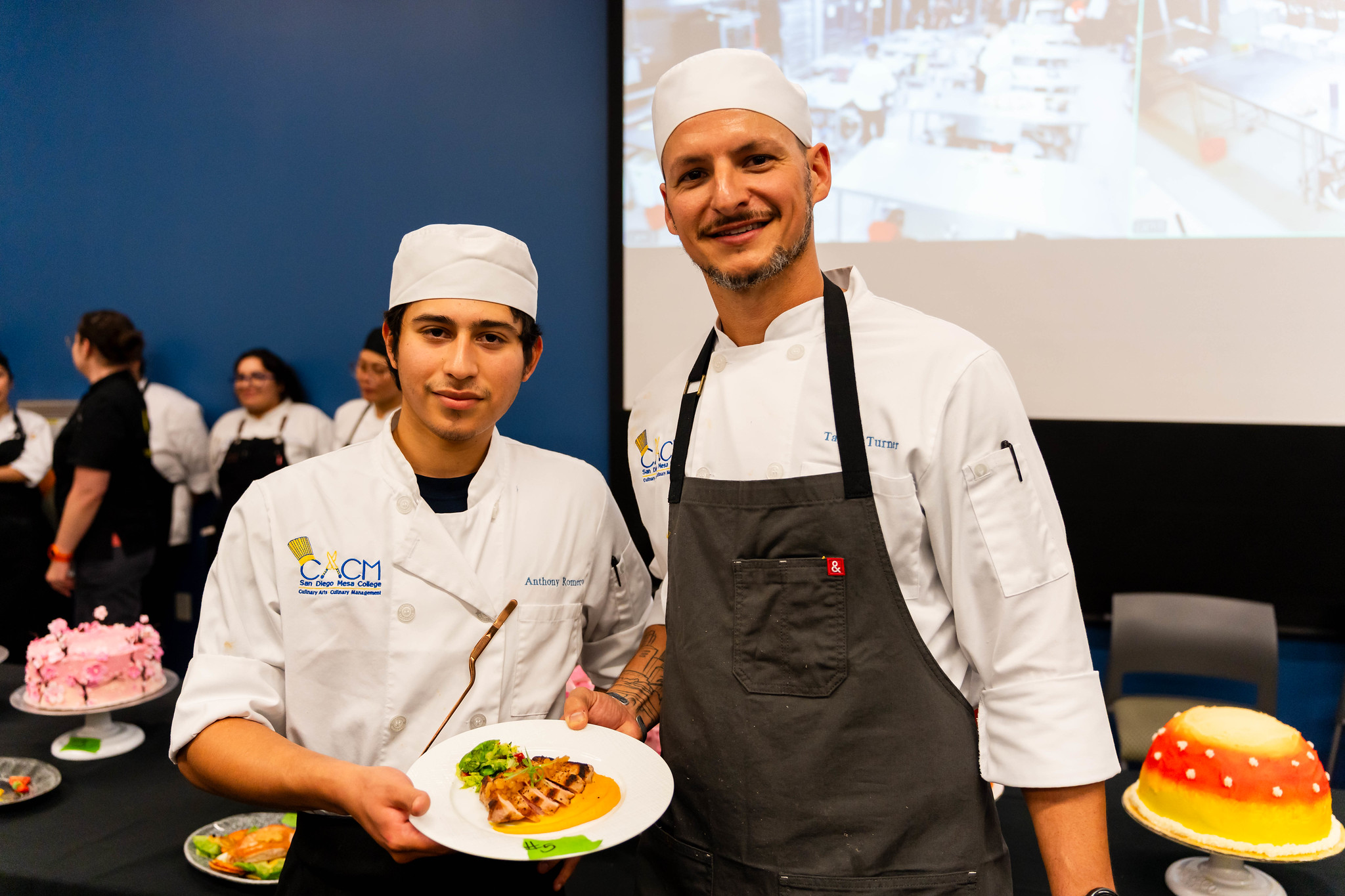 
Two chefs hold up a plate of food.
