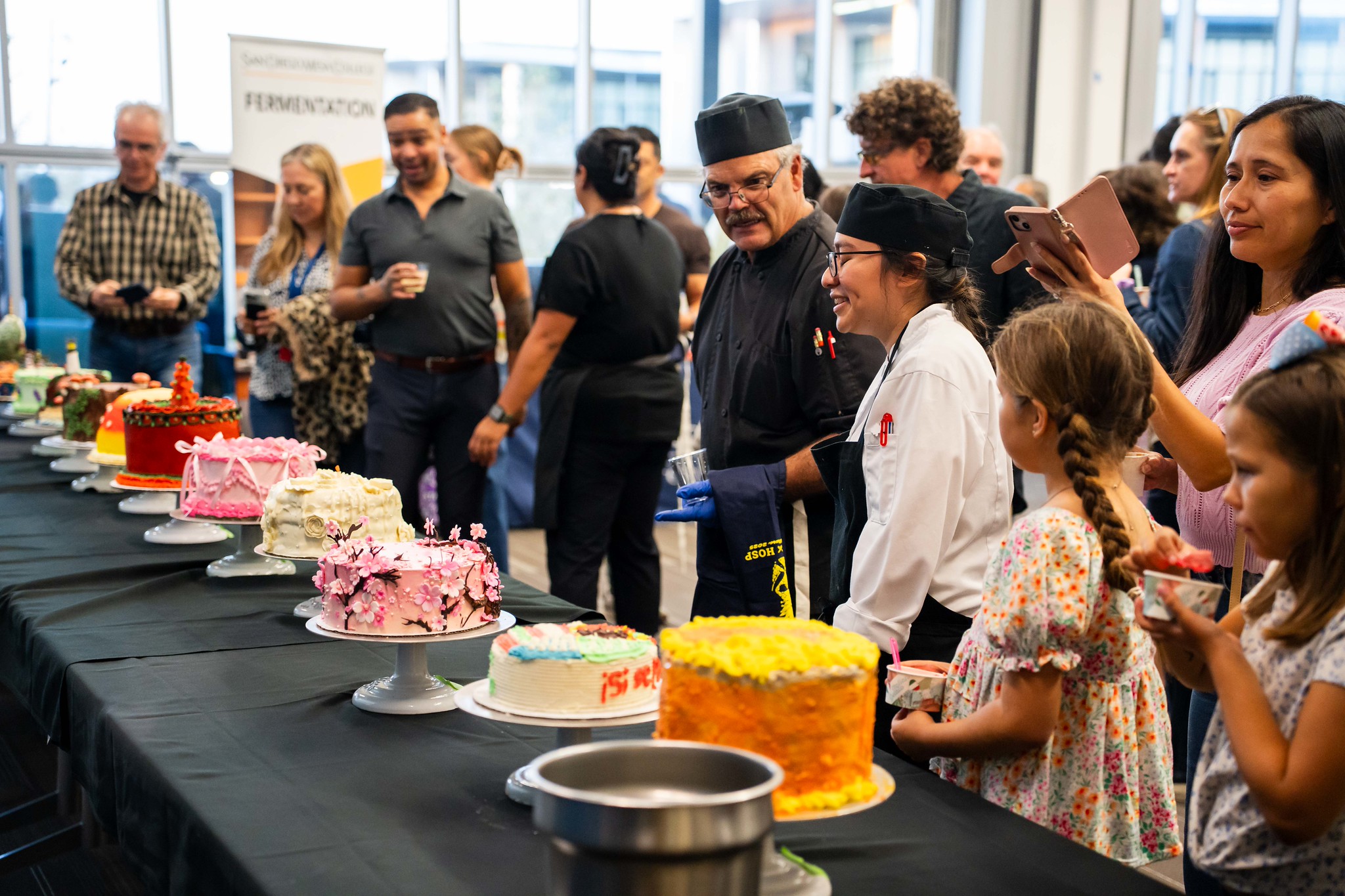 
A row of cakes lined up on tables for judging.
