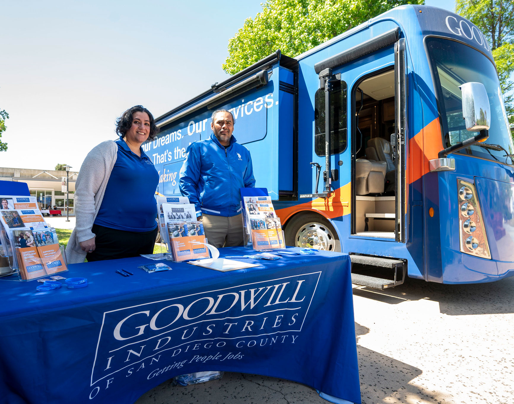 Two representatives from Goodwill and a Goodwill bus at the career fair.&nbsp;