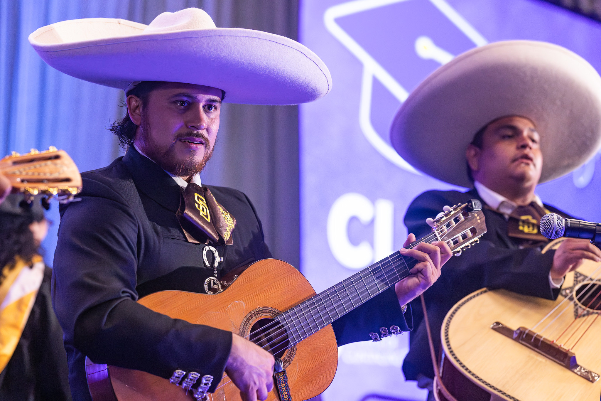 Two mariachi band members playing guitars.&nbsp;