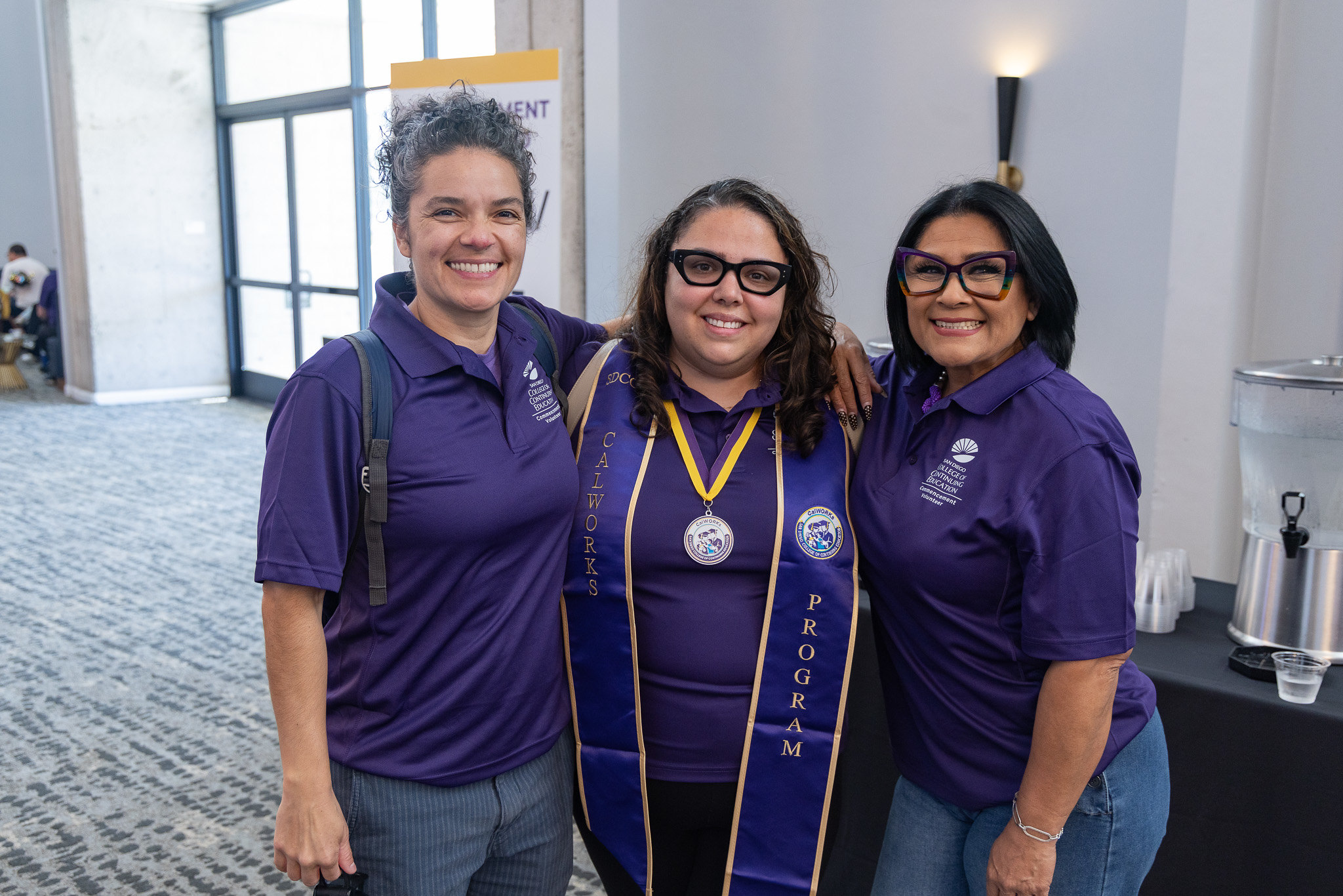Three college volunteers in the lobby at the ceremony.&nbsp;