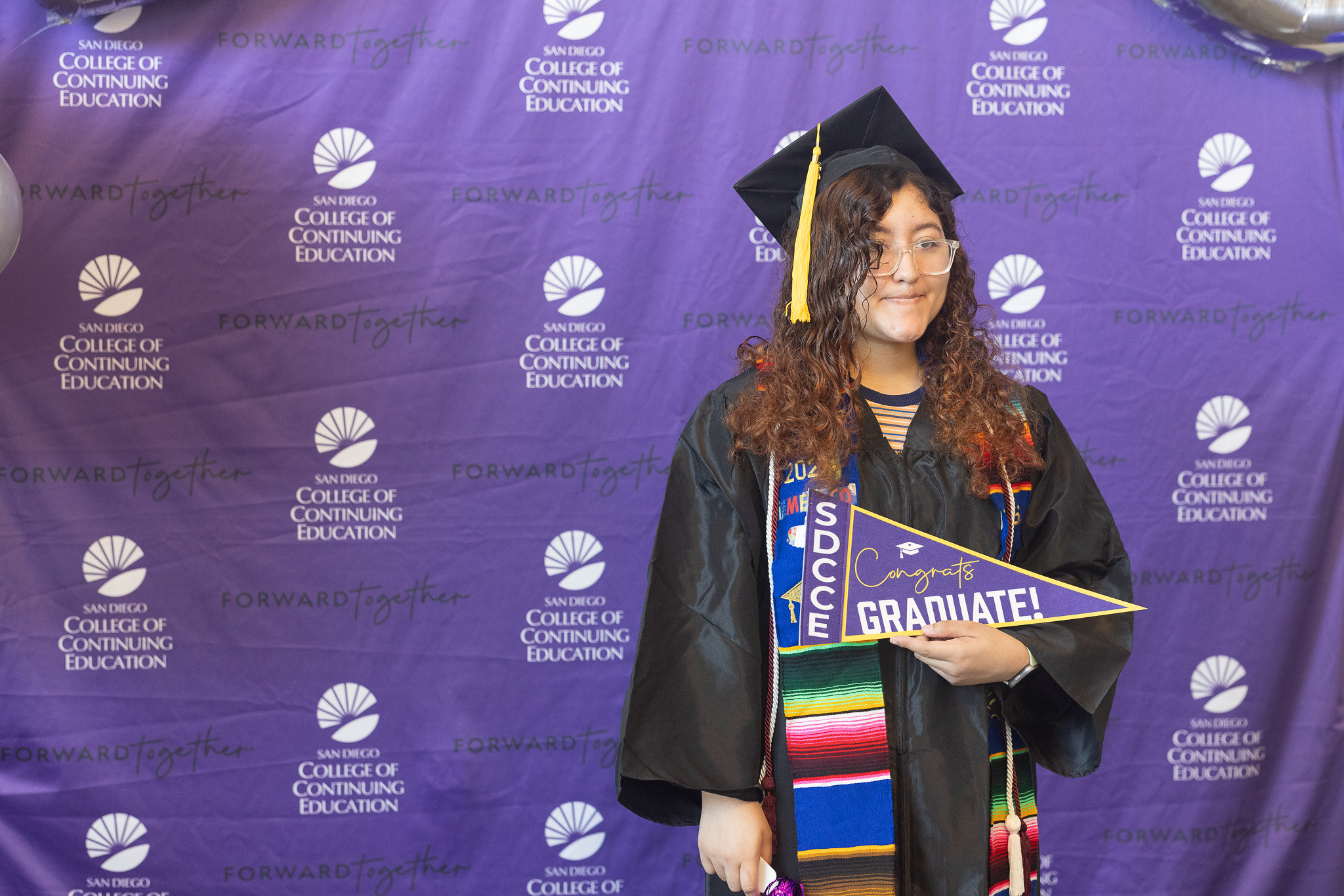 A student holds a purple graduate banner.