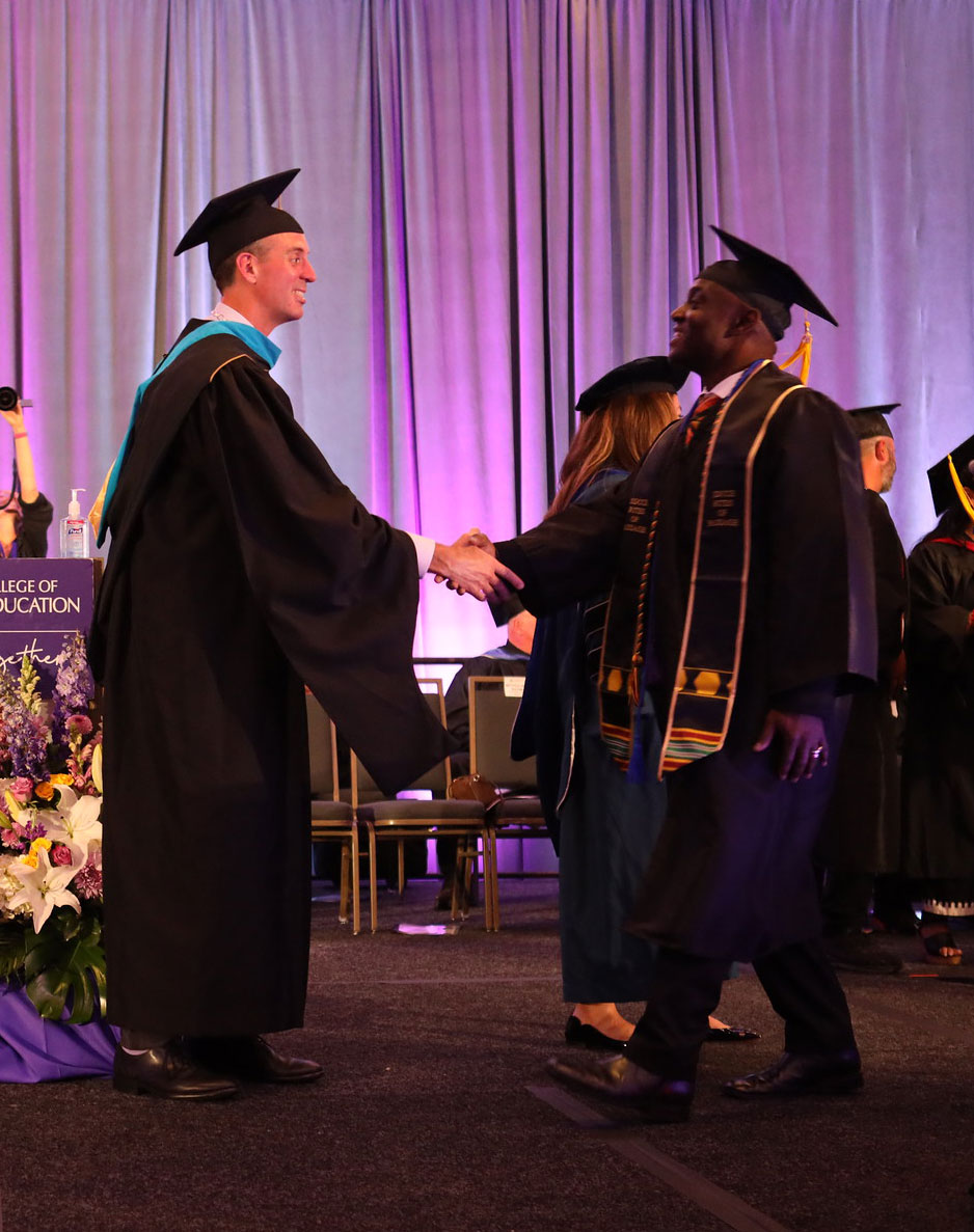 Chancellor Gregory Smith shakes a graduate's hand.