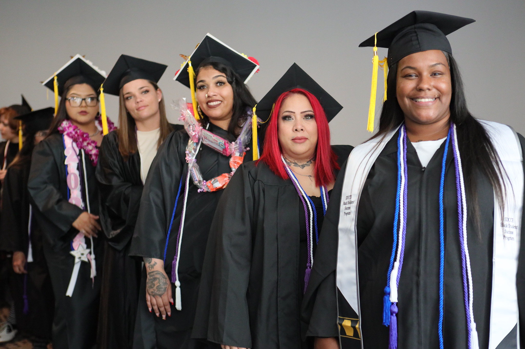 Five ladies in caps and gowns in the lobby at commencement.