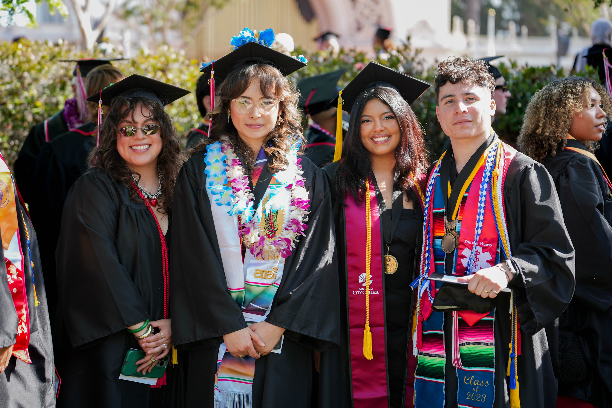 Four graduates pose together at commencement.&nbsp;