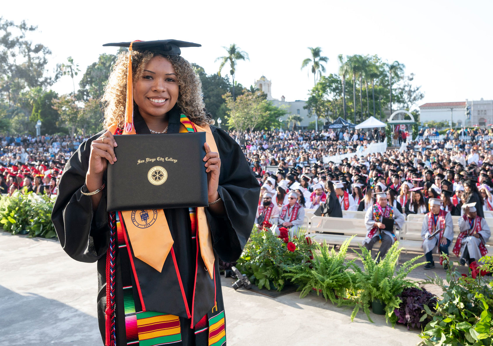 A student holds up her degree on stage.