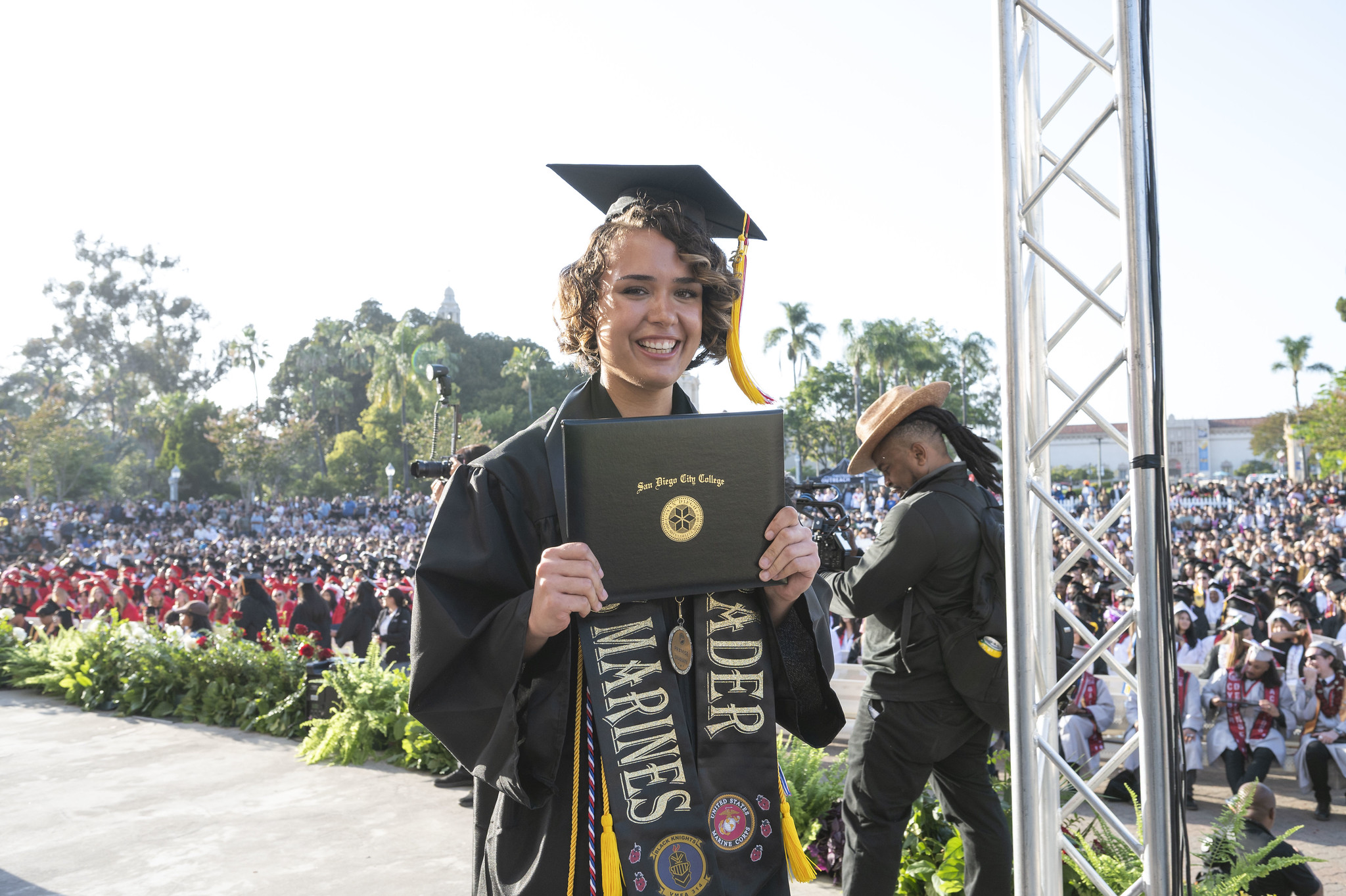 A student holds up her degree on stage.