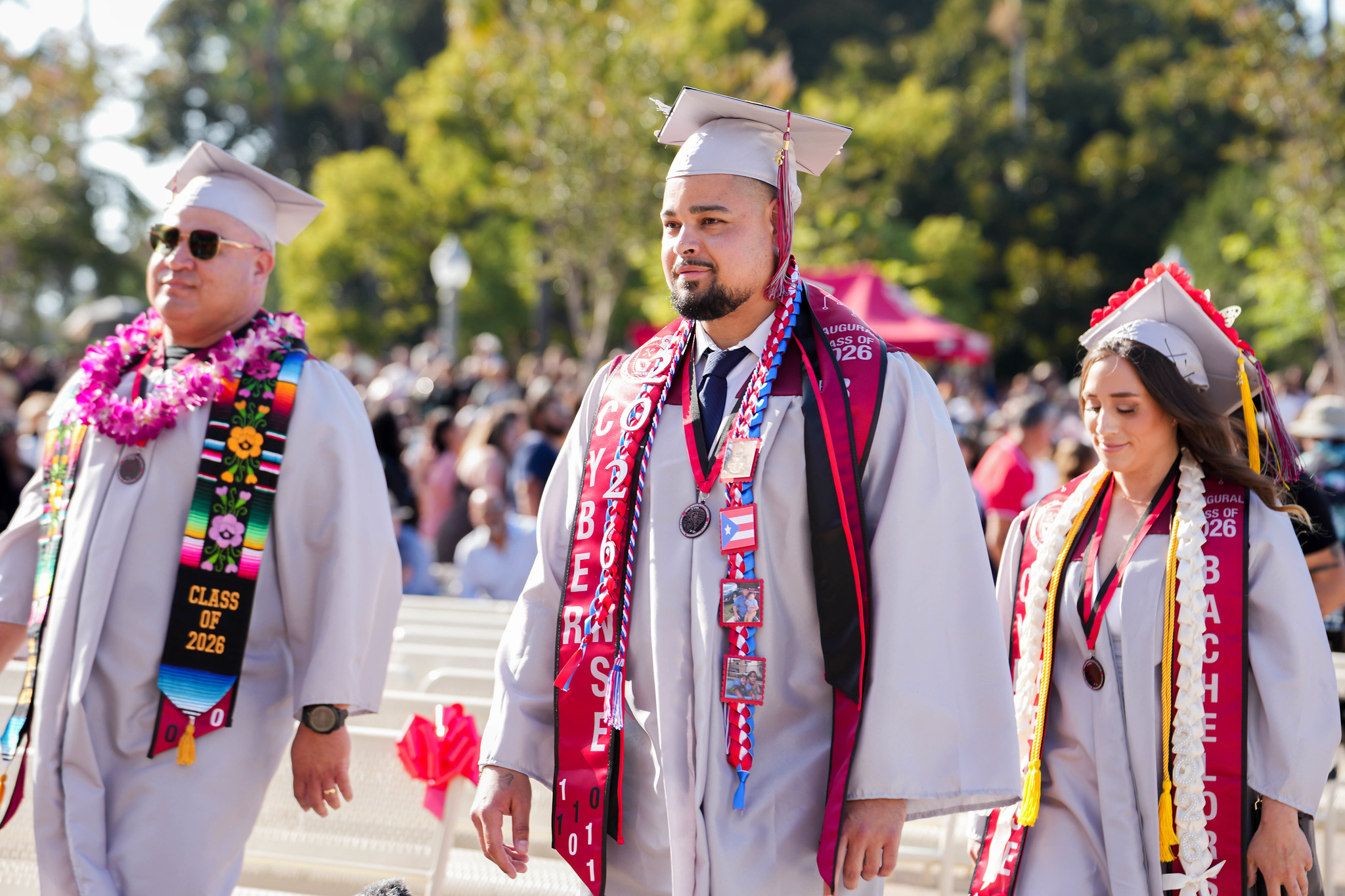 Three cyber defense graduates head to their seats.&nbsp;