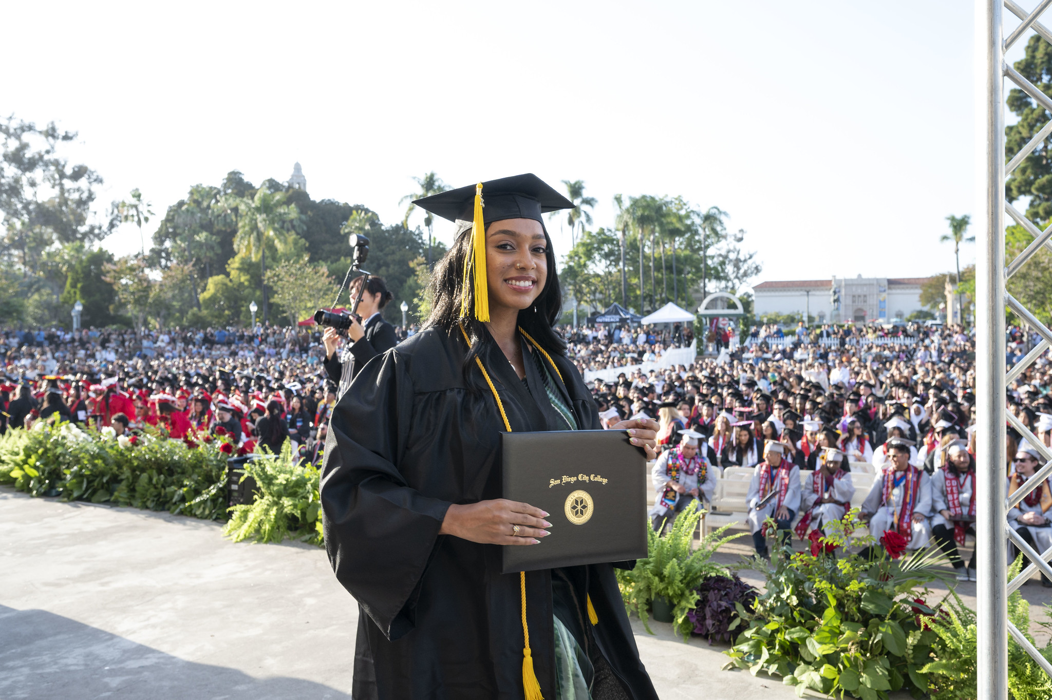 A student holds up her degree on stage.