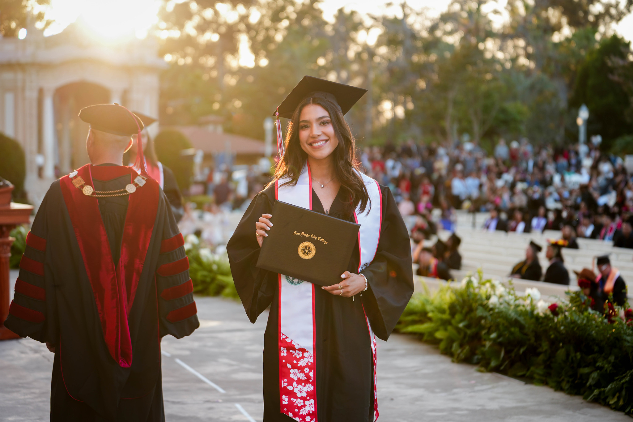 A student holds up her degree on stage.&nbsp;