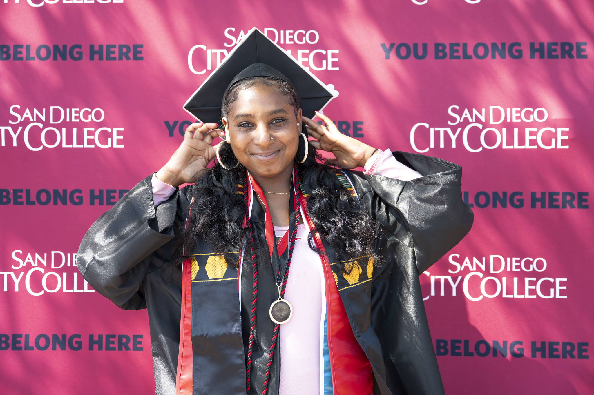 A graduate adjusts her cap for a photo.&nbsp;