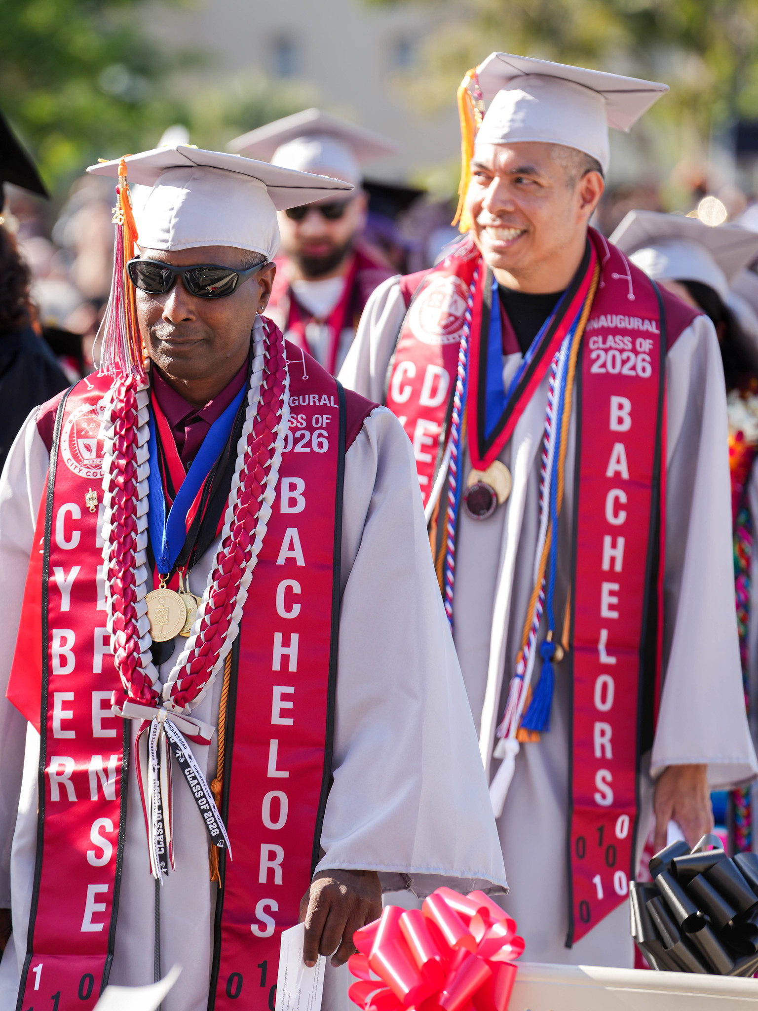 Two graduates in the cyber defense bachelor's degree program walk to their seats.&nbsp;