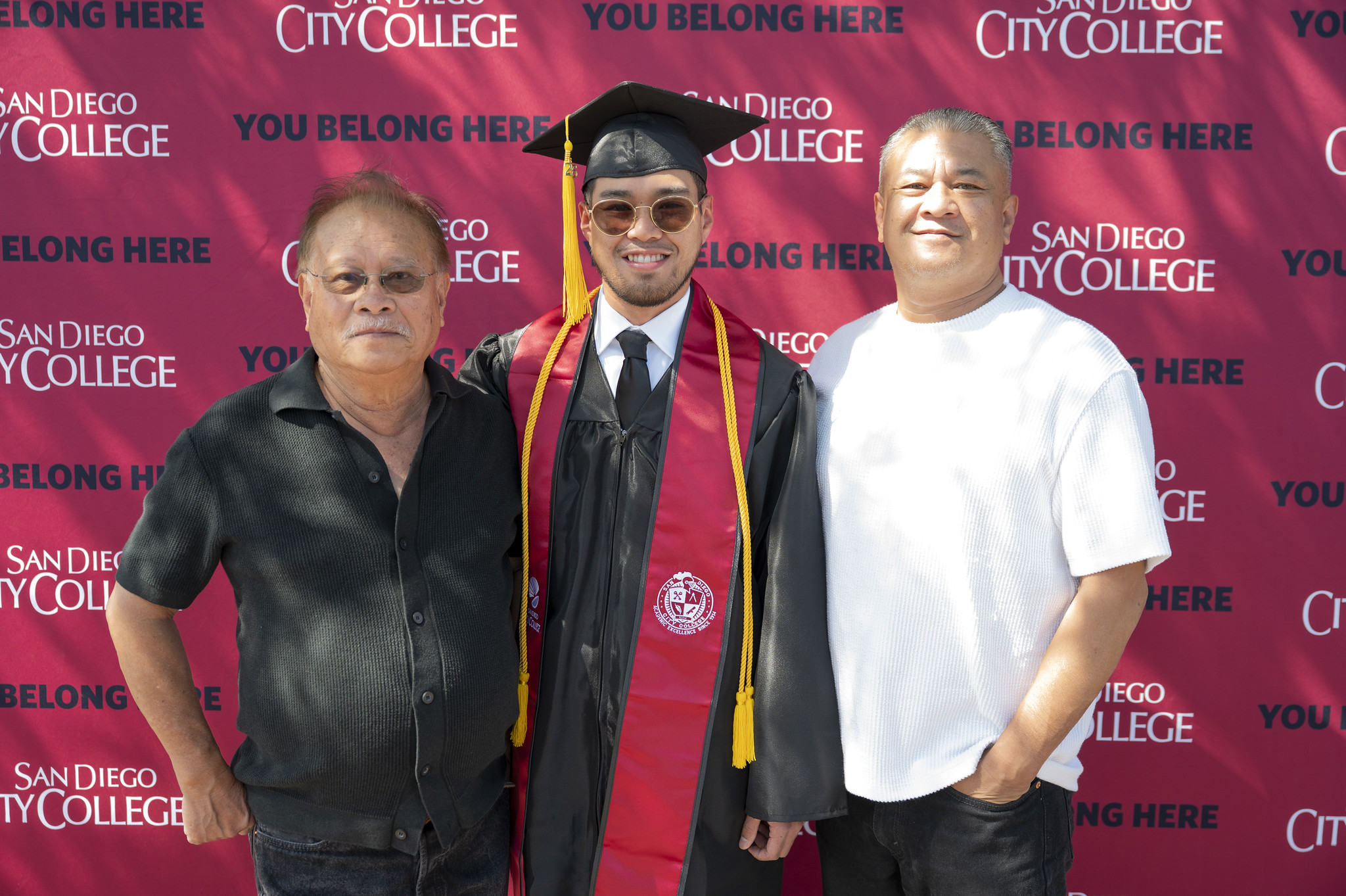 A graduate poses with two family members.