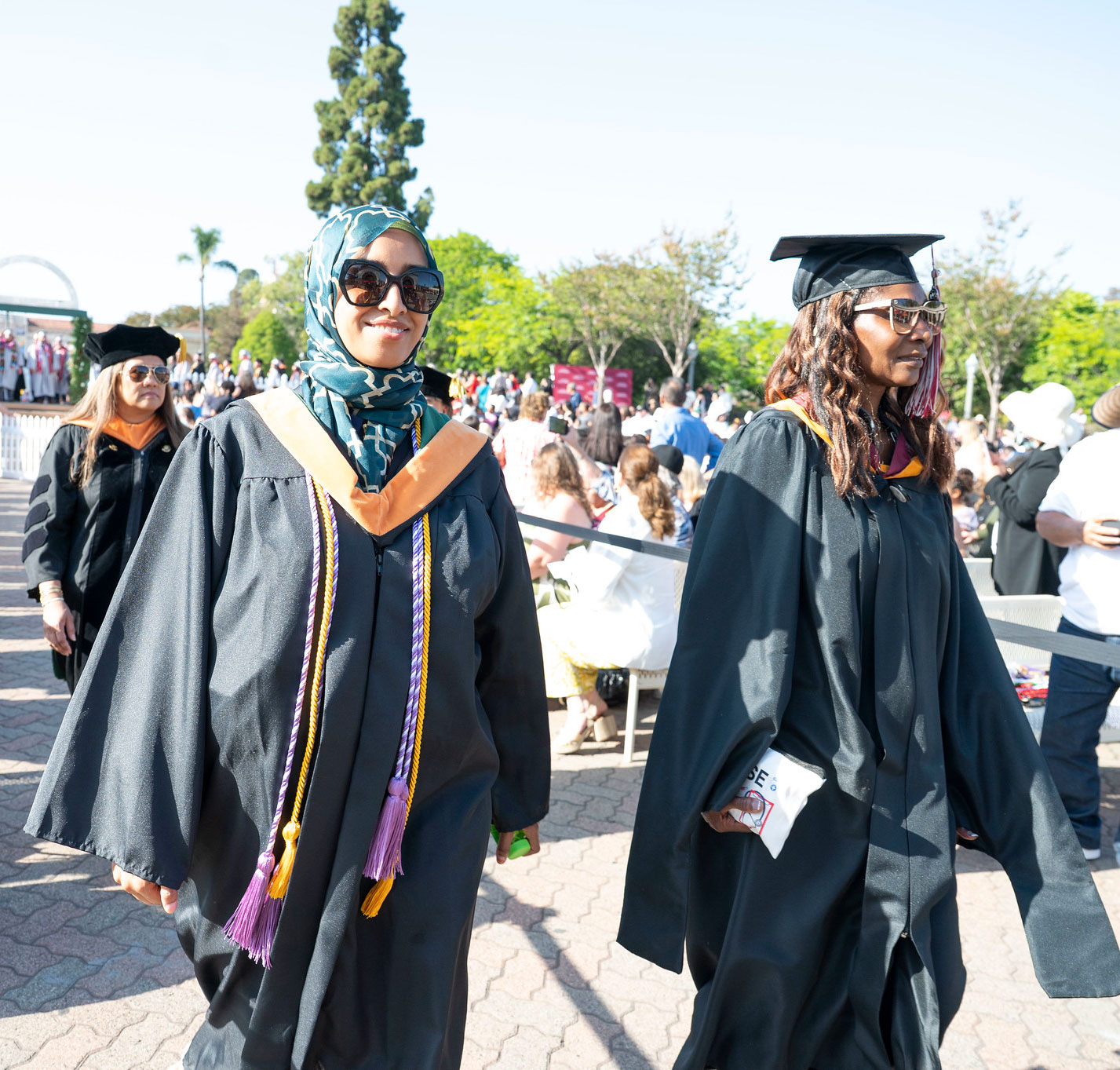 Two lines of graduates walk to their seats at the beginning of commencement.&nbsp;