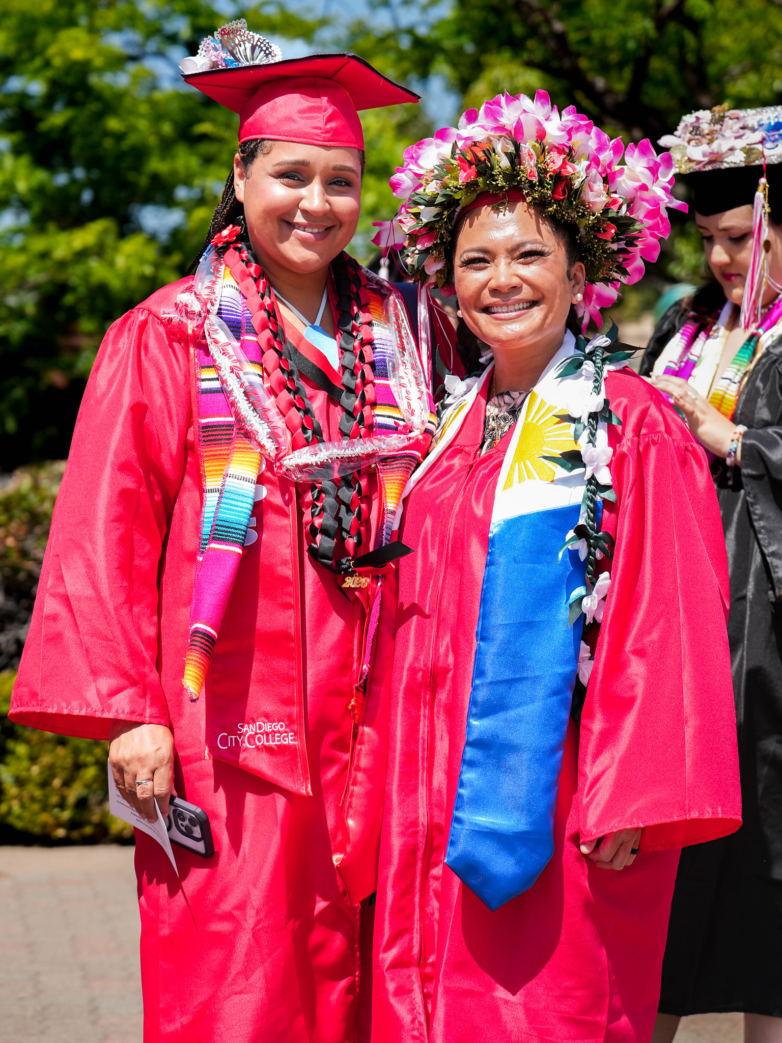 Two graduates in red caps and gowns.&nbsp;