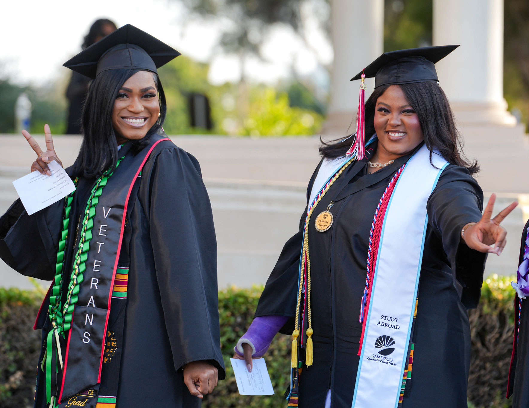 Two graduates wave to the audience as they head to the stage.&nbsp;