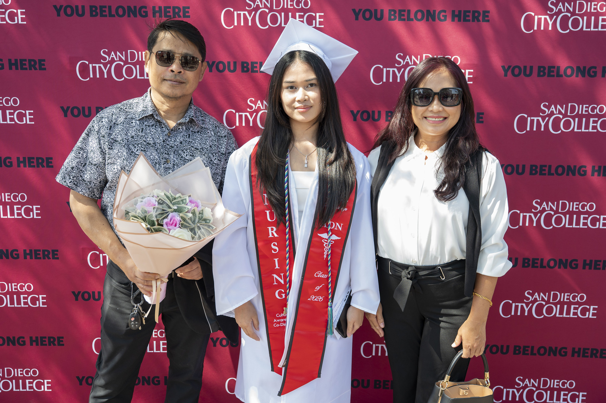 A graduate poses with two family members.&nbsp;