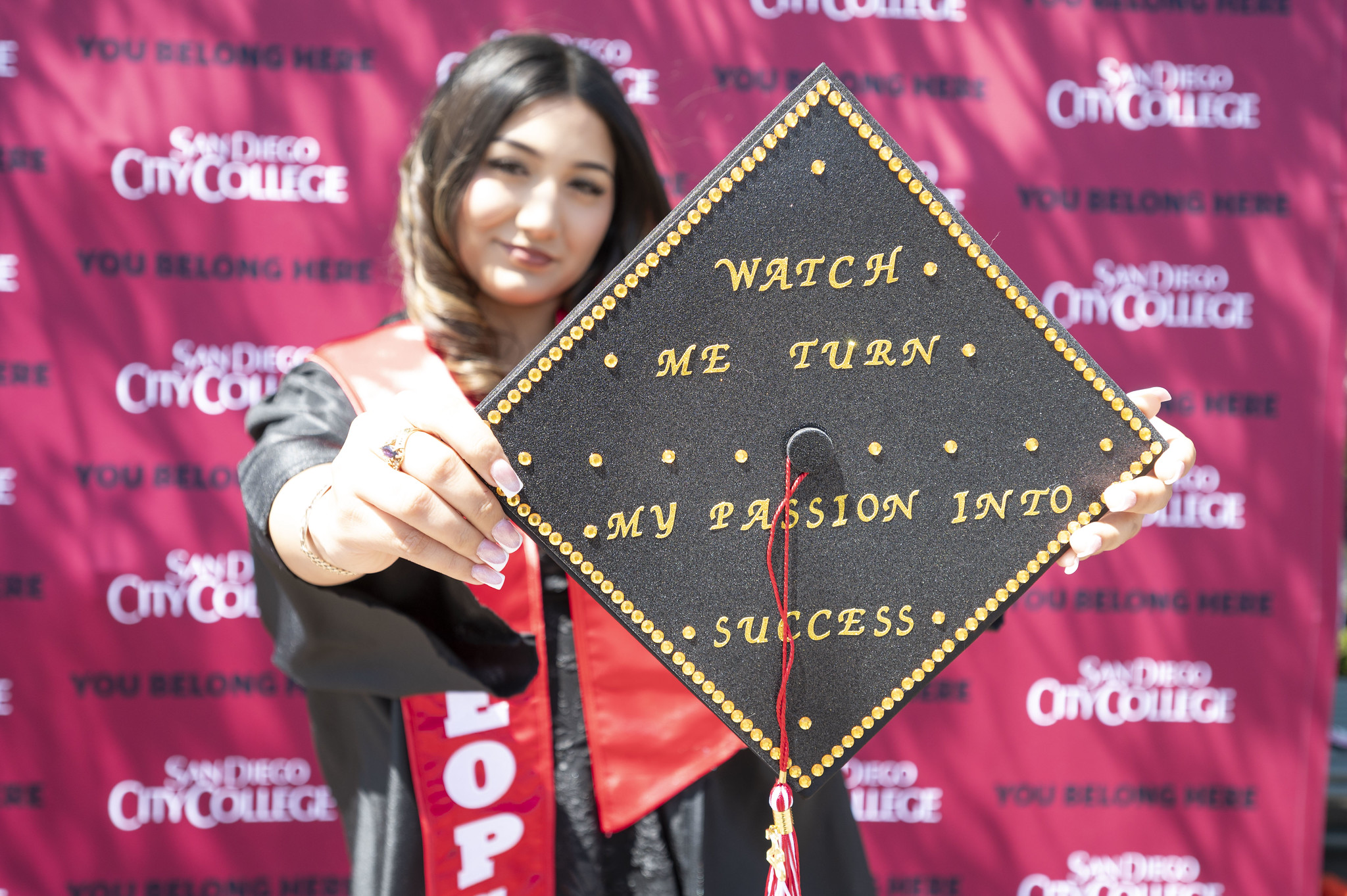 A graduate holds up her decorated cap that says Watch me turn my passion into success.