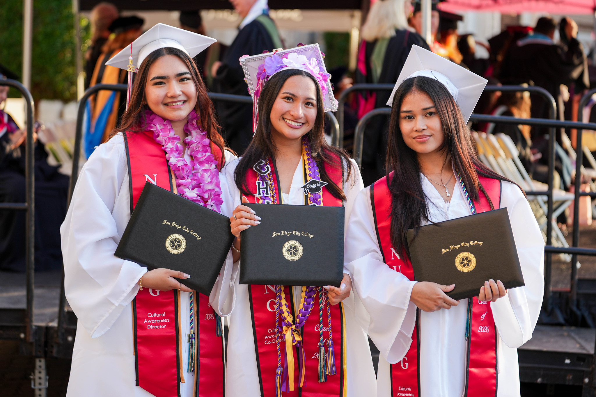 Three graduates from the nursing program hold up their degrees.&nbsp;