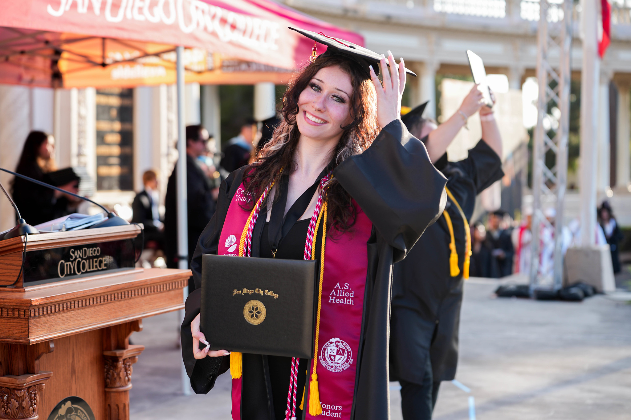 A graduate holds up her degree on stage.