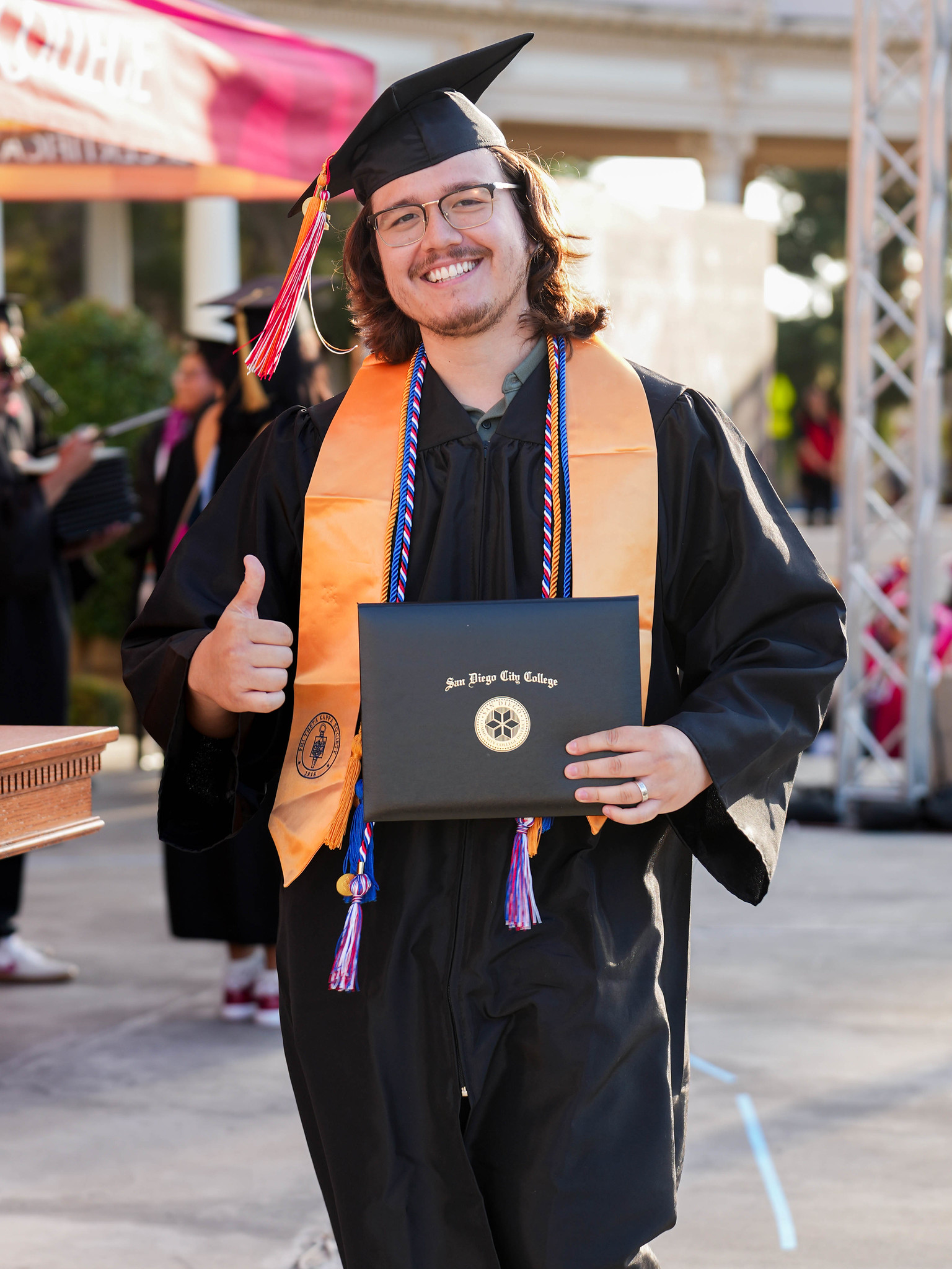 A graduate holds up his degree on stage.&nbsp;