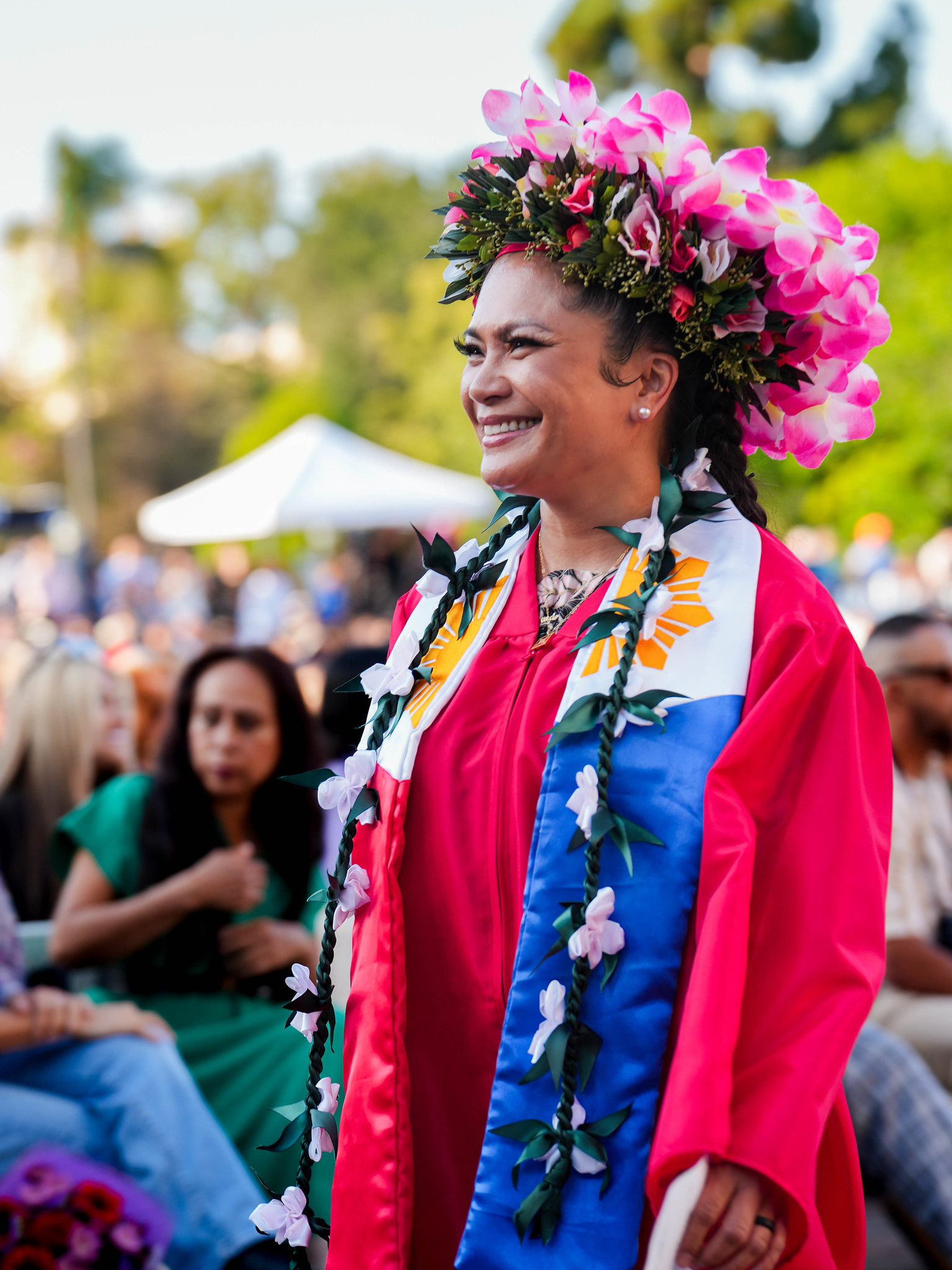 A graduate with a cap decorated with bright pink flowers.&nbsp;