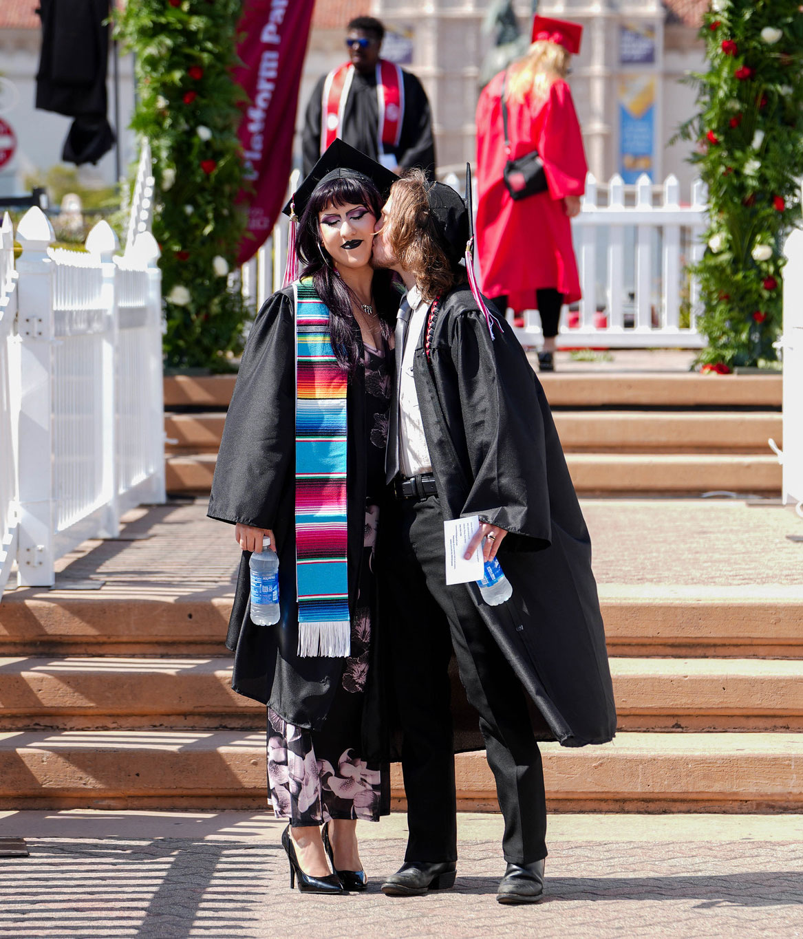 Two graduates kiss before the start of the ceremony.